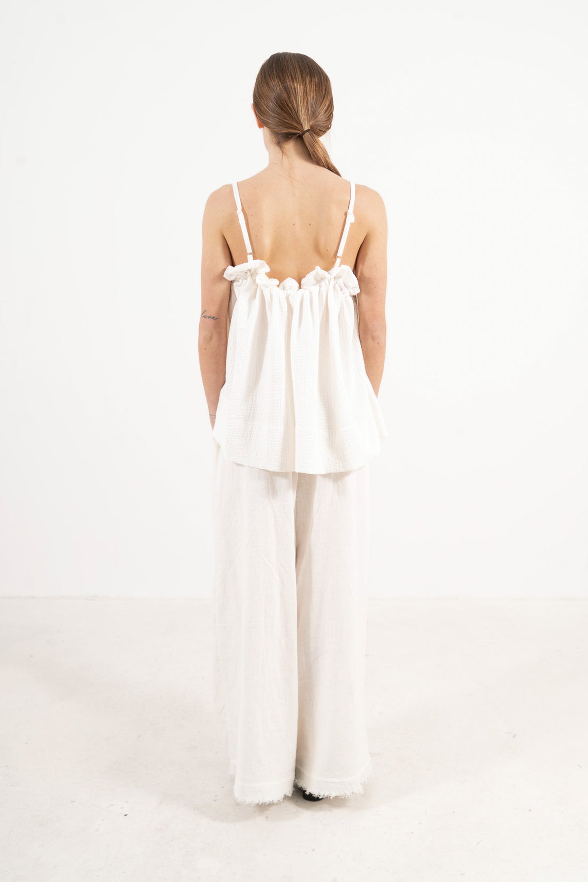 Minimalist back view of the cotton top on a model, illustrating a softly elevated look and timeless aesthetic.