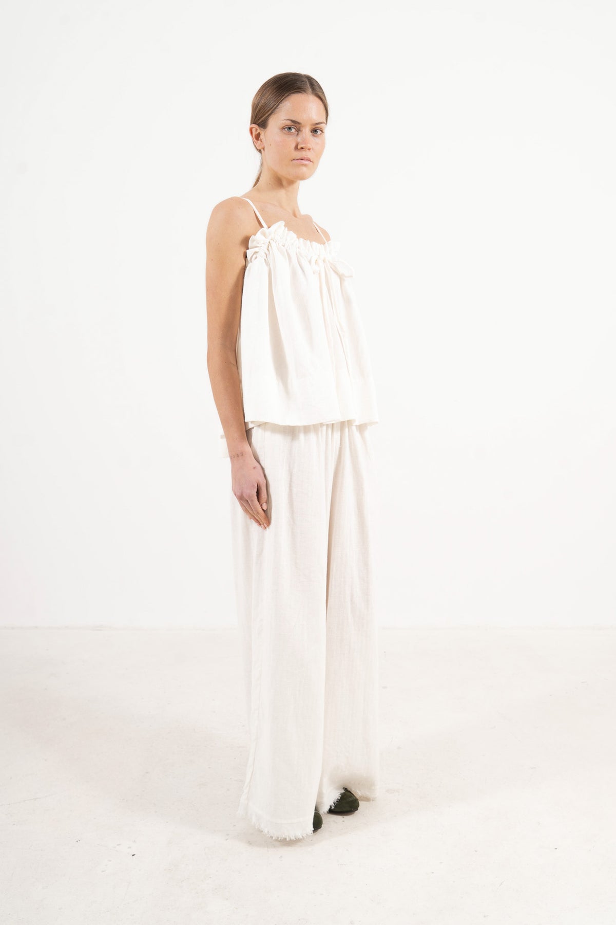 A sophisticated profile view of the standalone MOCHA Adeline top in white soft cotton, revealing its graceful design lines resting on a clean white surface.