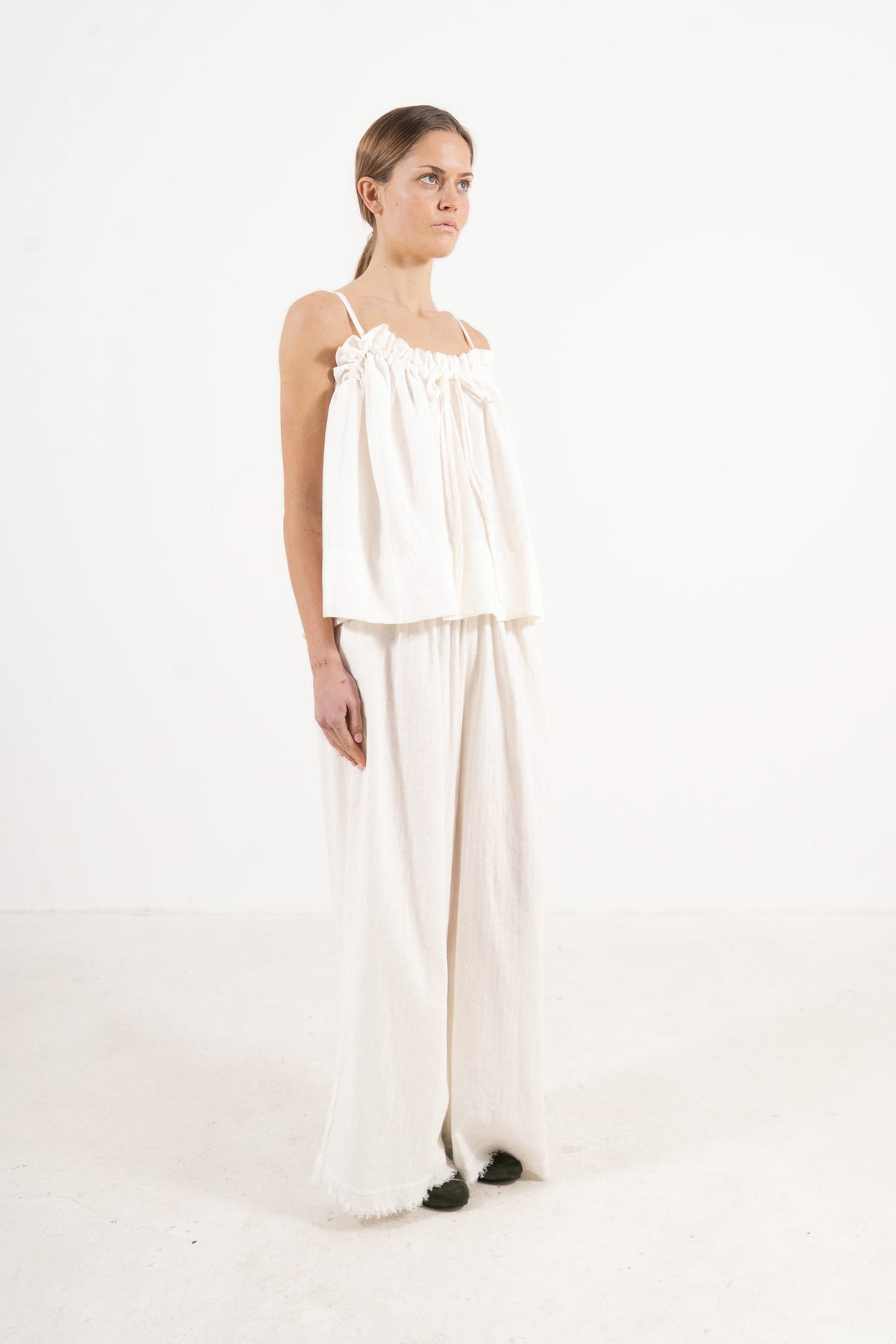 A poetic side angle view of the luxury soft cotton MOCHA Adeline top, showcasing its timeless silhouette cascading softly against a white backdrop.