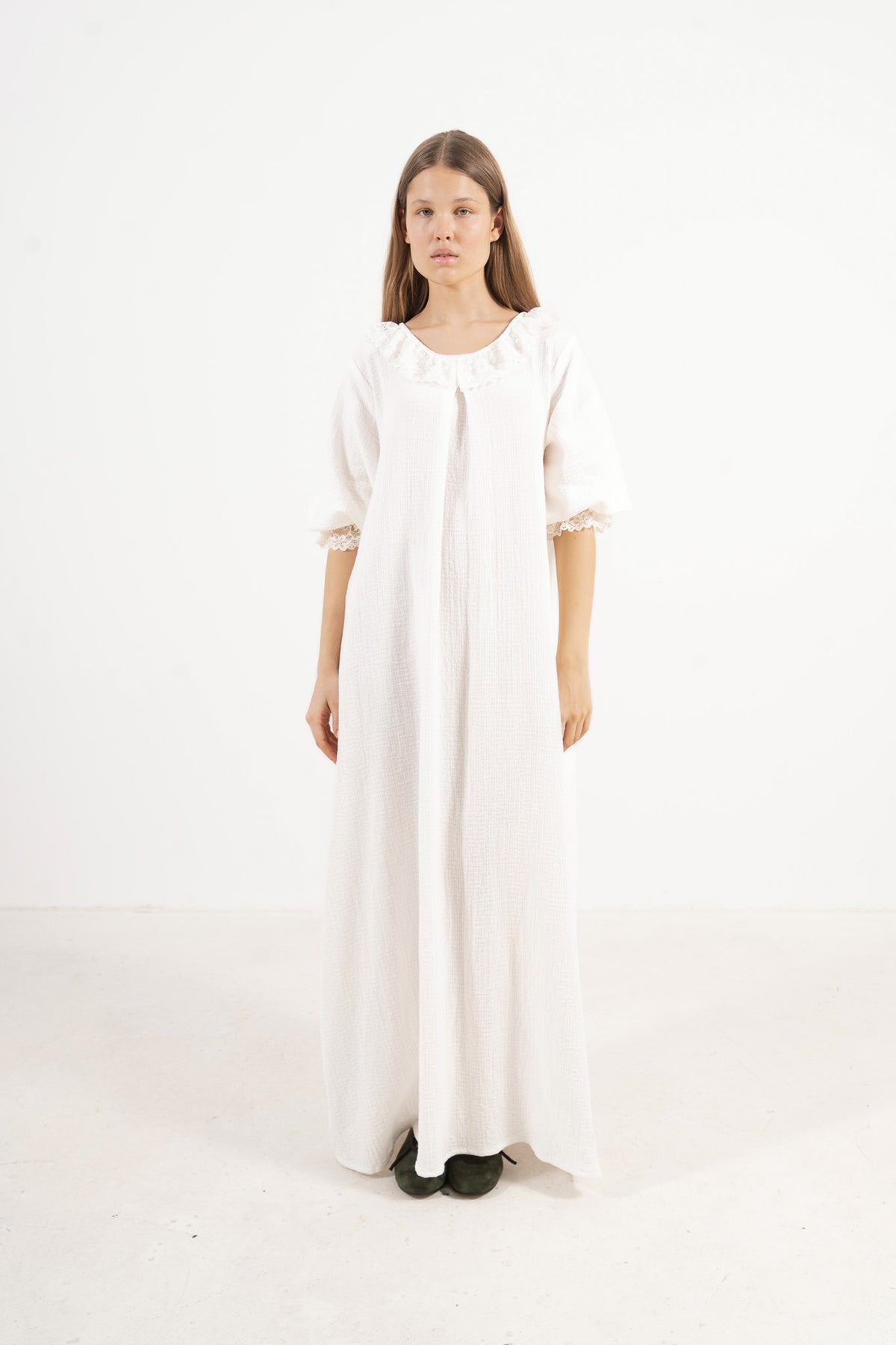 An elegant front view of the MOCHA Aérienne long dress, meticulously crafted from the finest pure soft cotton, draped beautifully upon a pristine white floor.