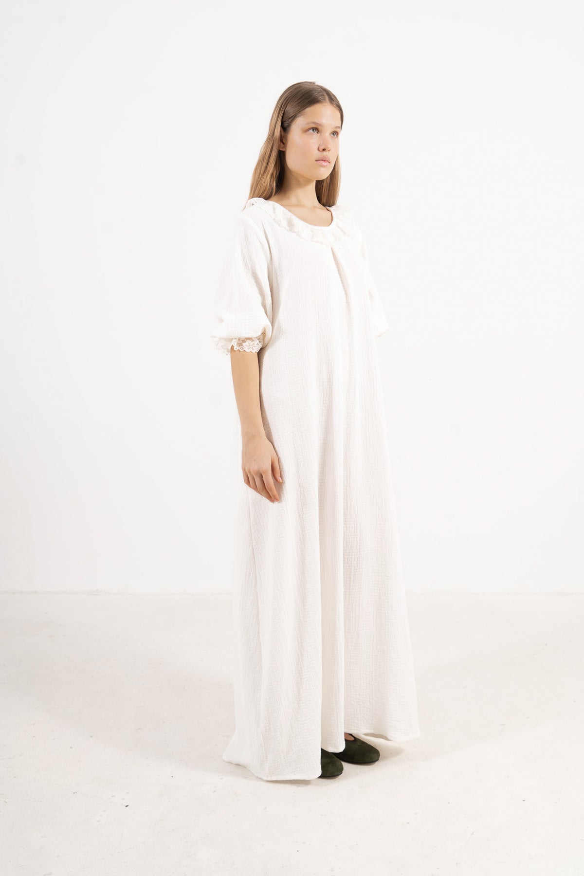 A sophisticated profile view of the standalone MOCHA Aérienne dress in white soft cotton, revealing its graceful design lines resting on a clean white surface.