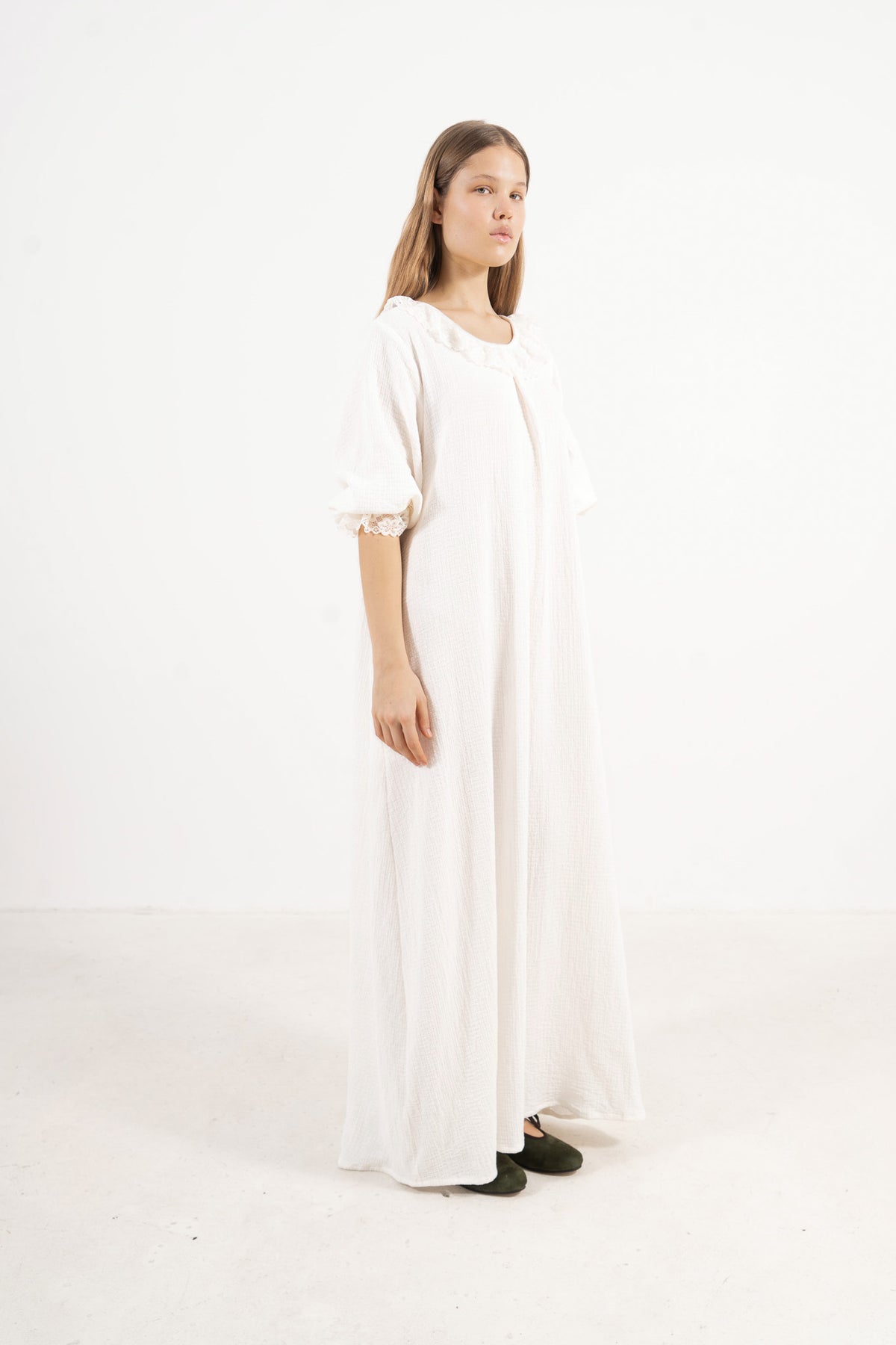 A sophisticated profile view of the standalone MOCHA Aérienne dress in white soft cotton, revealing its graceful design lines resting on a clean white surface.