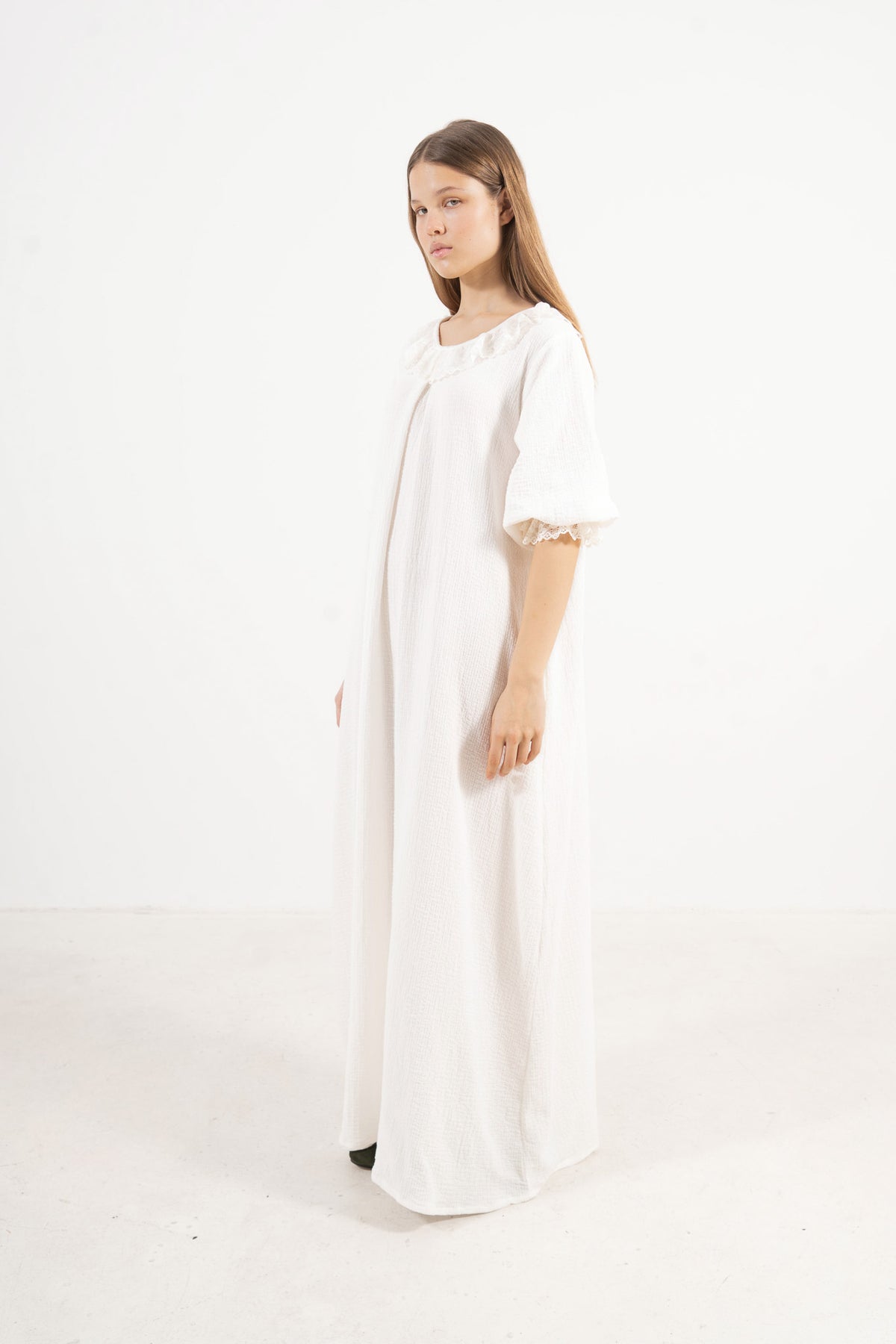 A poetic side angle view of the luxury soft cotton MOCHA Aérienne garment, showcasing its light, timeless silhouette cascading softly against a white backdrop.