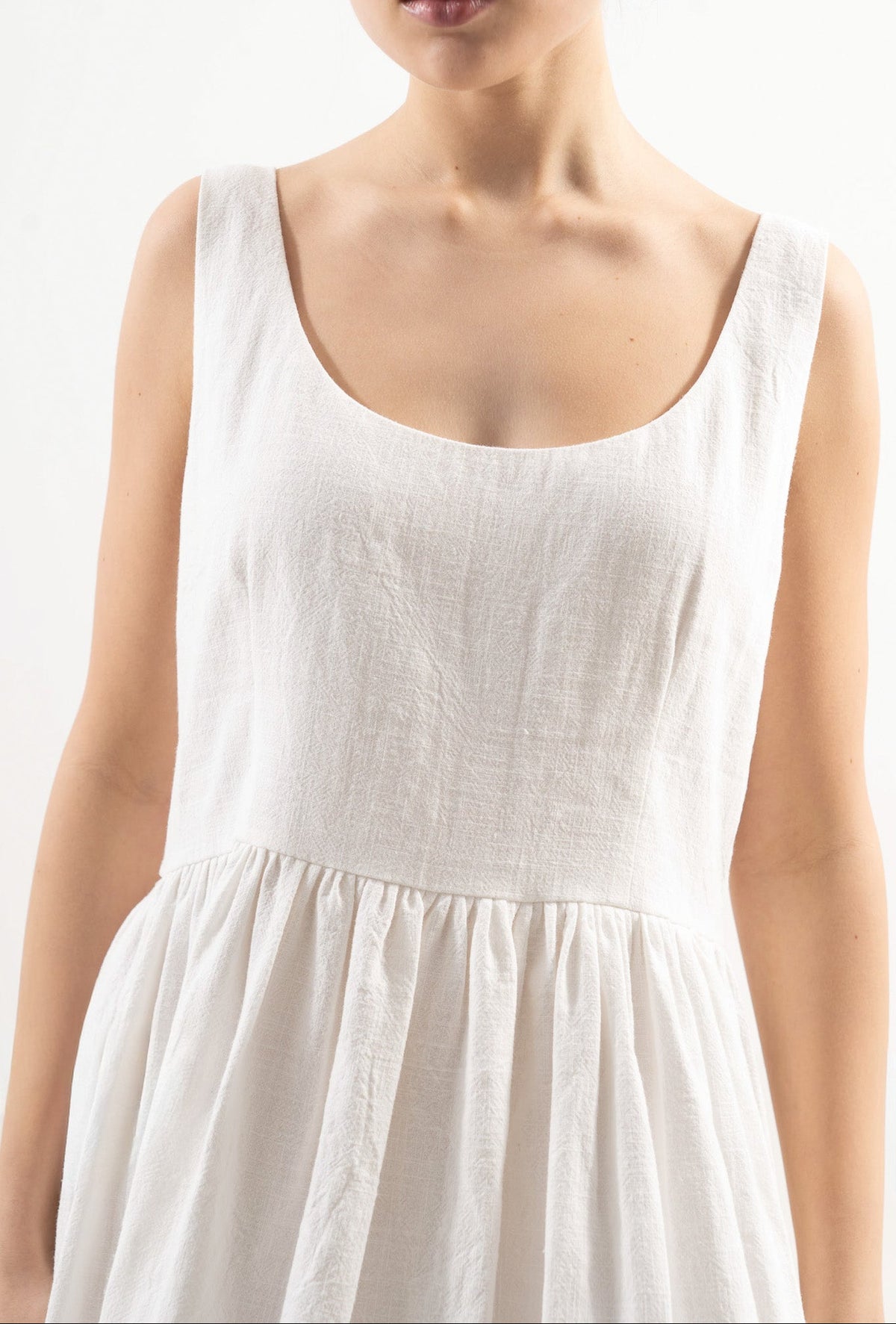 An exquisite close-up detail of the MOCHA Amandine dress, celebrating the fine cotton and ramie weave, gentle structural elements, and superior fabric texture.