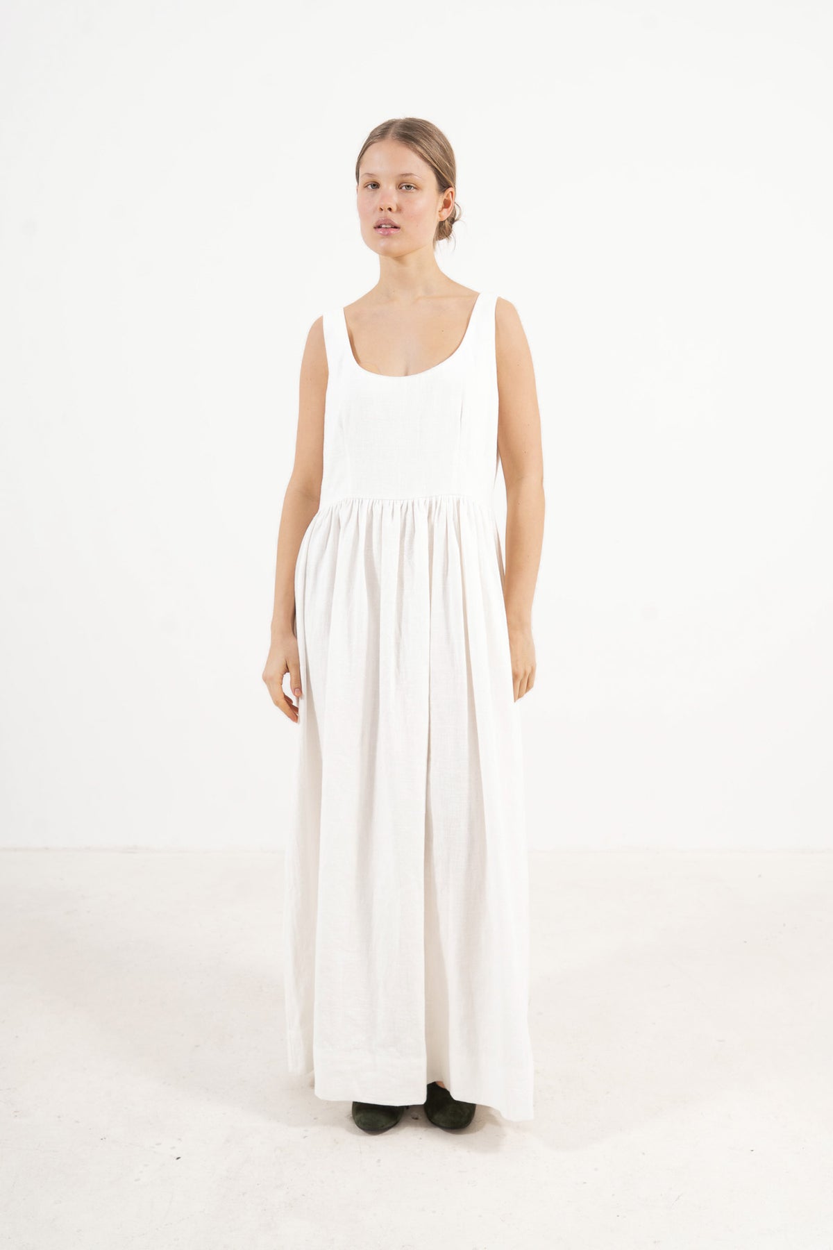 A sophisticated profile view of the standalone MOCHA Amandine dress in cotton and ramie, revealing its graceful design lines resting on a clean white surface.