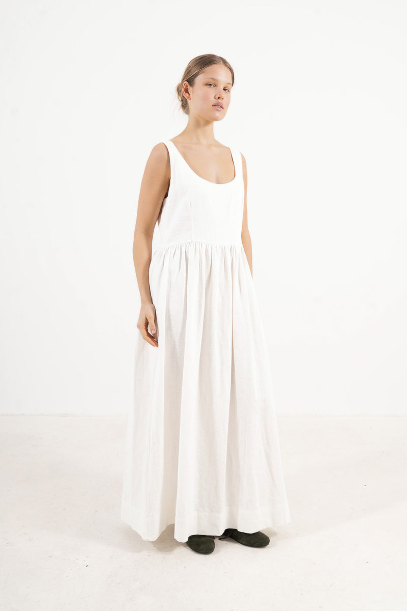A sophisticated profile view of the standalone MOCHA Amandine dress in cotton and ramie, revealing its graceful design lines resting on a clean white surface.