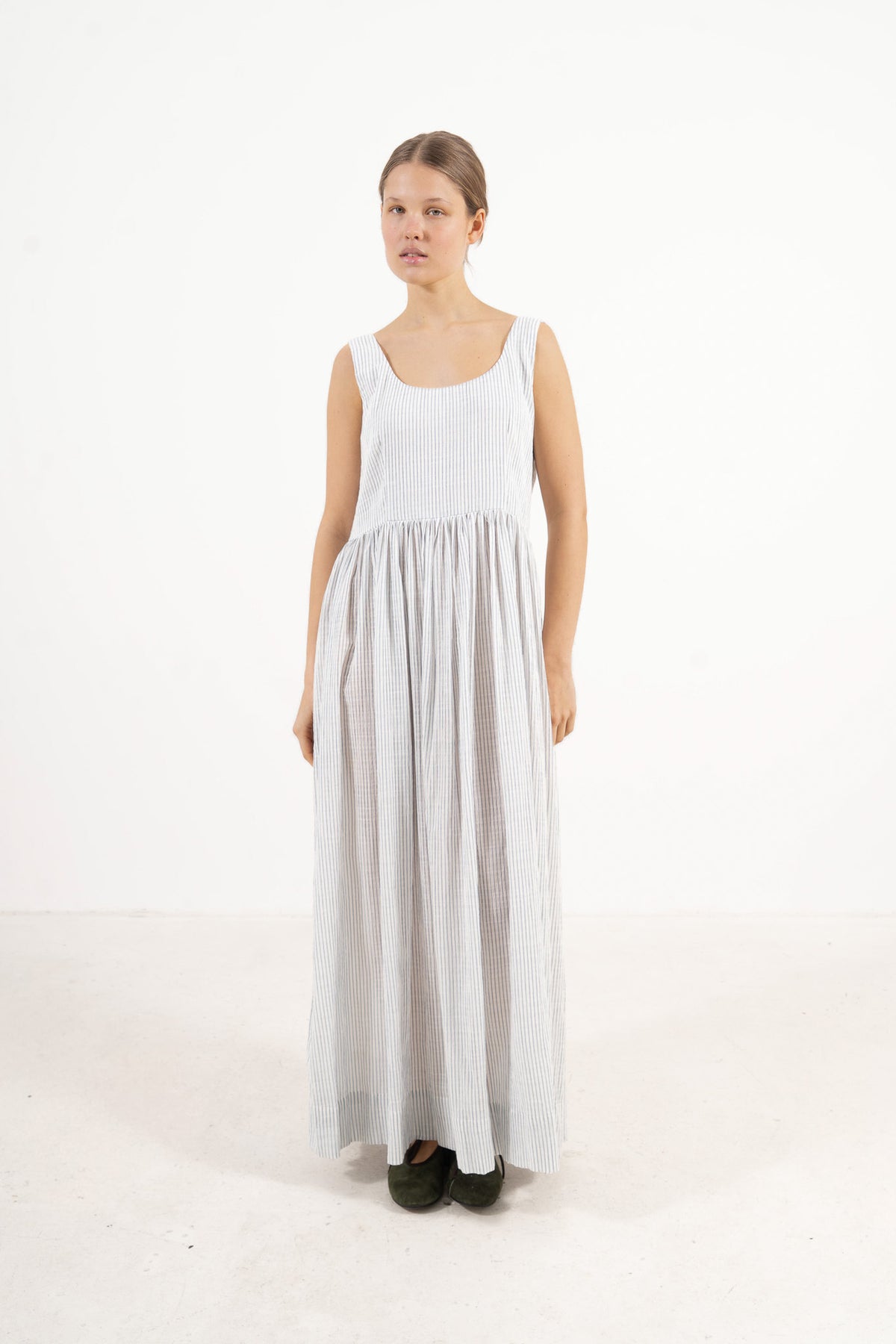  Front view studio portrait featuring a model in the fine-striped Amandine long dress by MOCHA, capturing a soft world of lightness and ease.