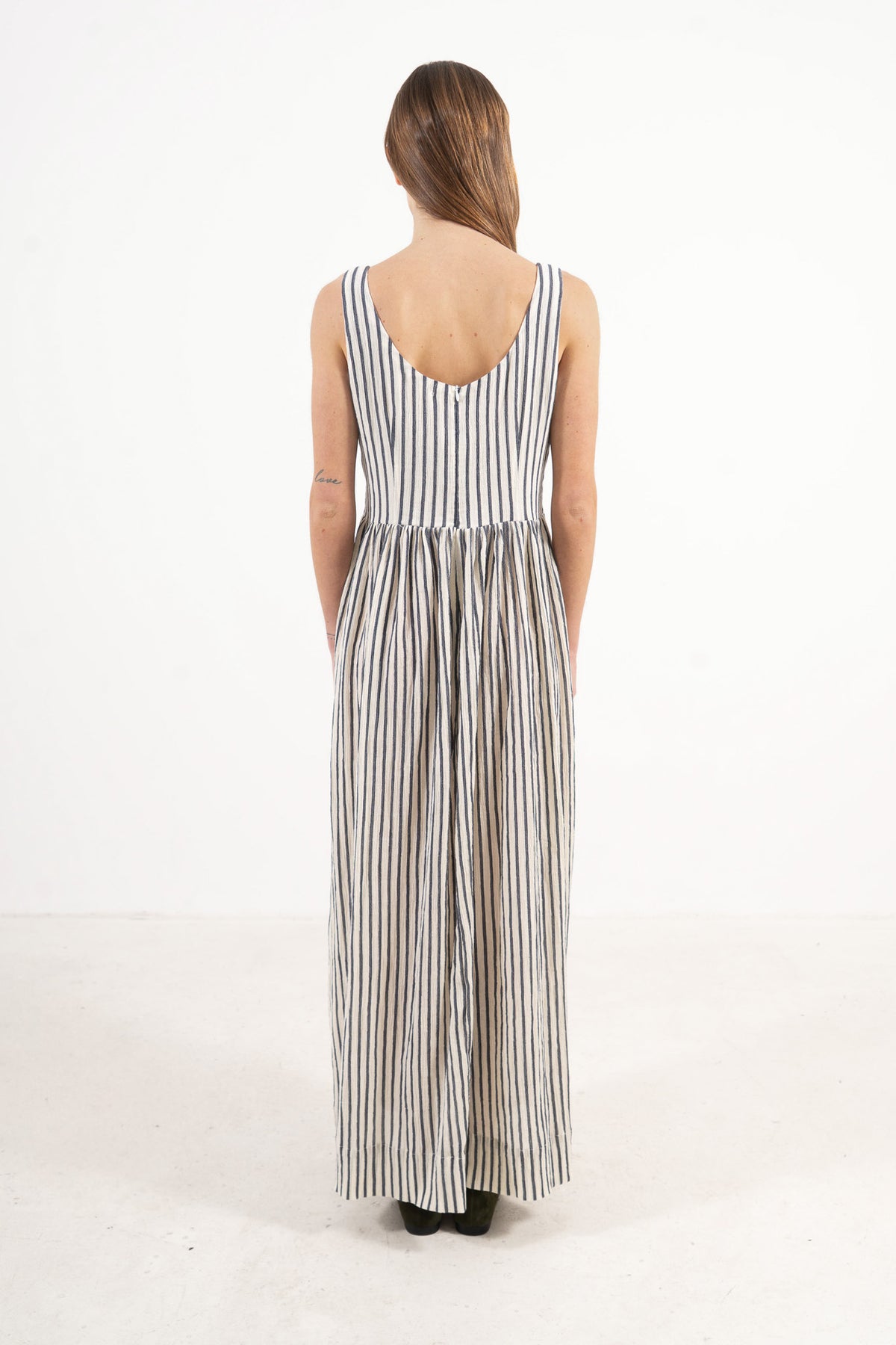 Back view of the timeless long cotton dress on a model, capturing the gentle aesthetic and understated elegance of the piece.