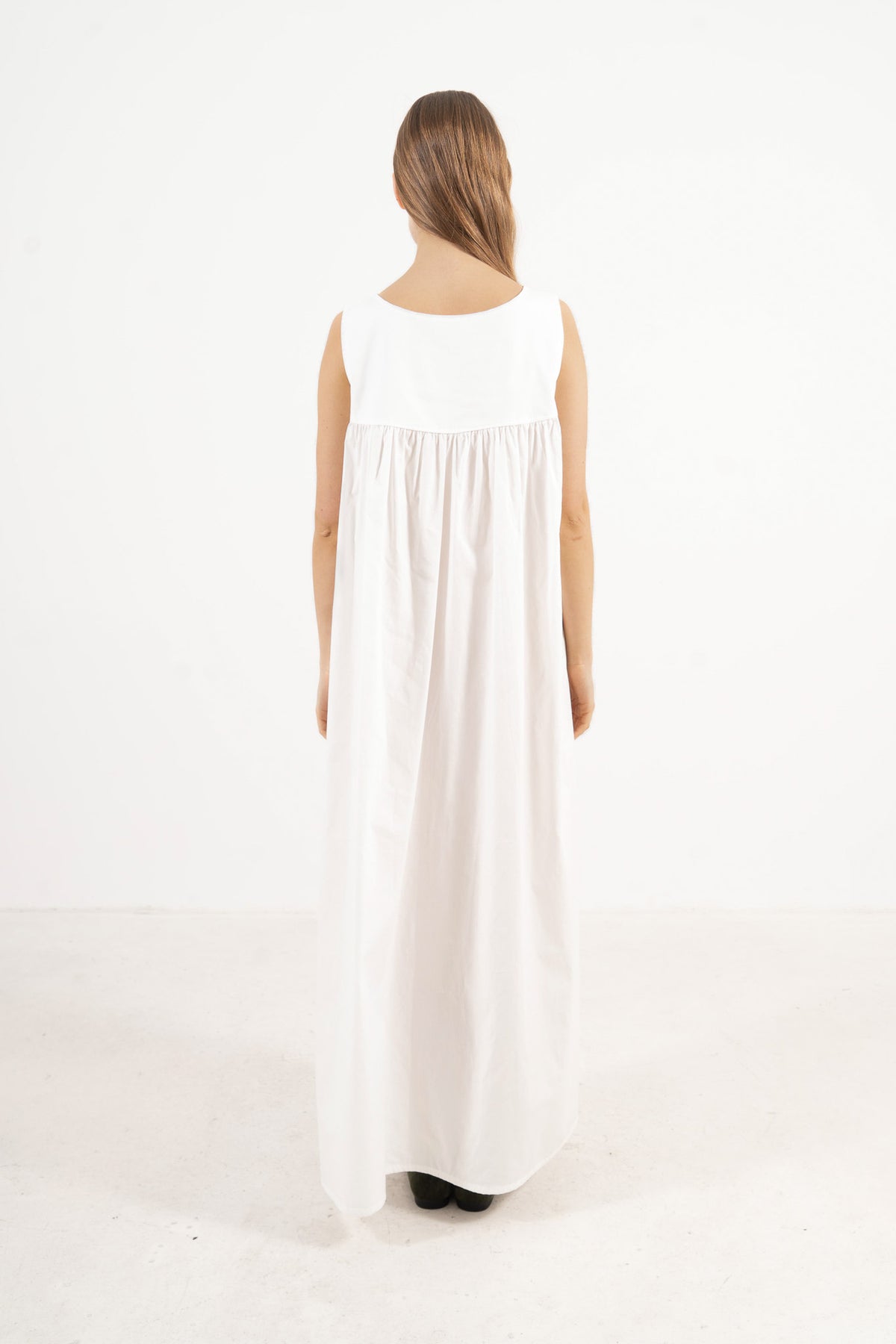 Back view of the timeless long cotton dress on a model, capturing a gentle aesthetic inspired by air, movement, and calm days.