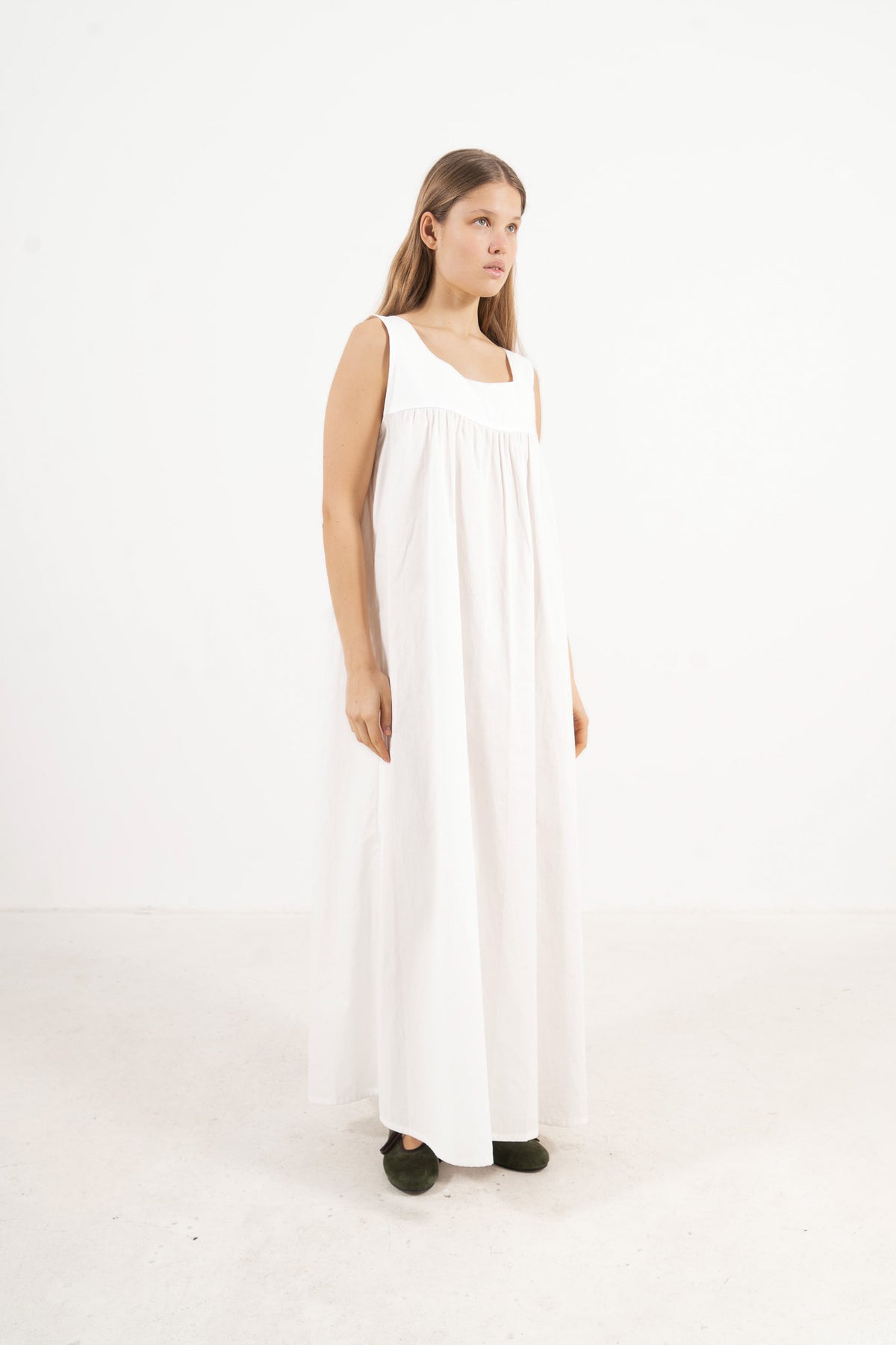 Side lookbook capture of the white cotton dress, emphasizing how the flowing fabric and generous length move easily with every step.