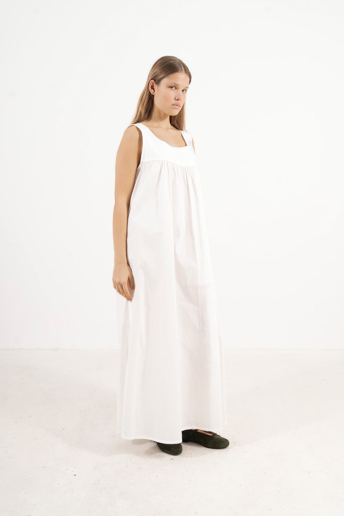 Side lookbook capture of the white cotton dress, emphasizing how the flowing fabric and generous length move easily with every step.