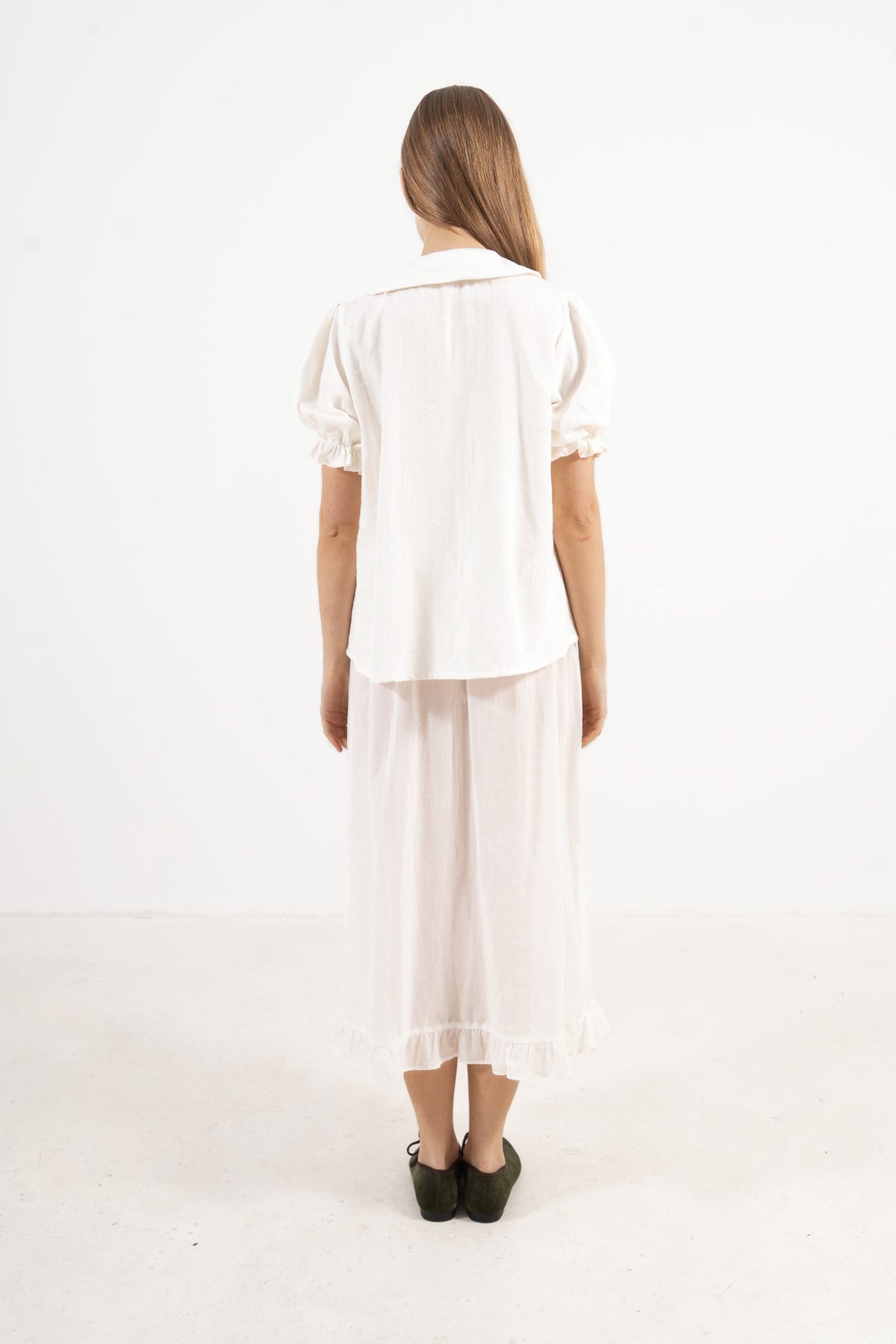 Back view of the timeless cotton blouse on a model, capturing a soft world of lightness and understated femininity.