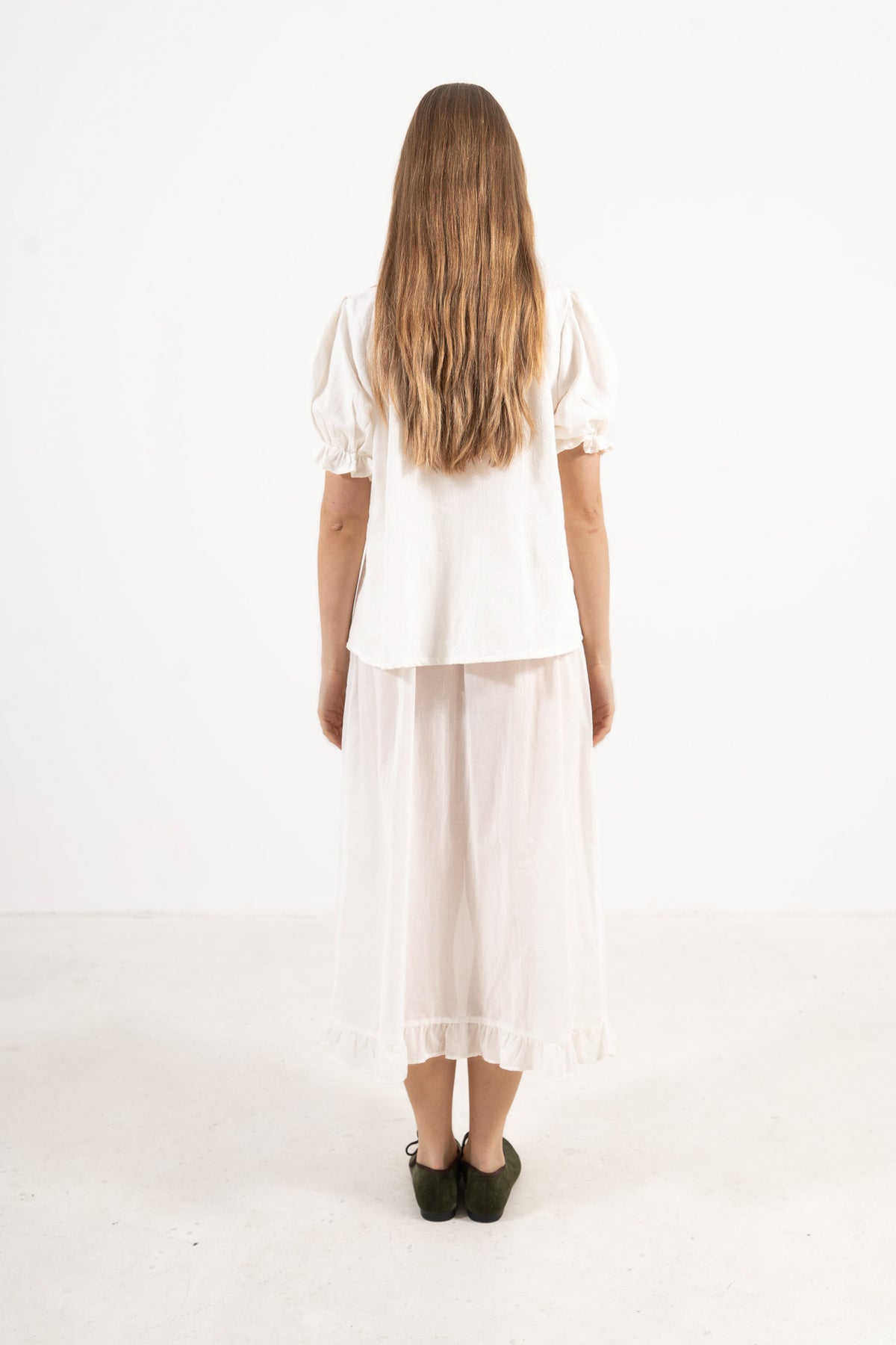 Back view of the timeless cotton blouse on a model, capturing a soft world of lightness and understated femininity.