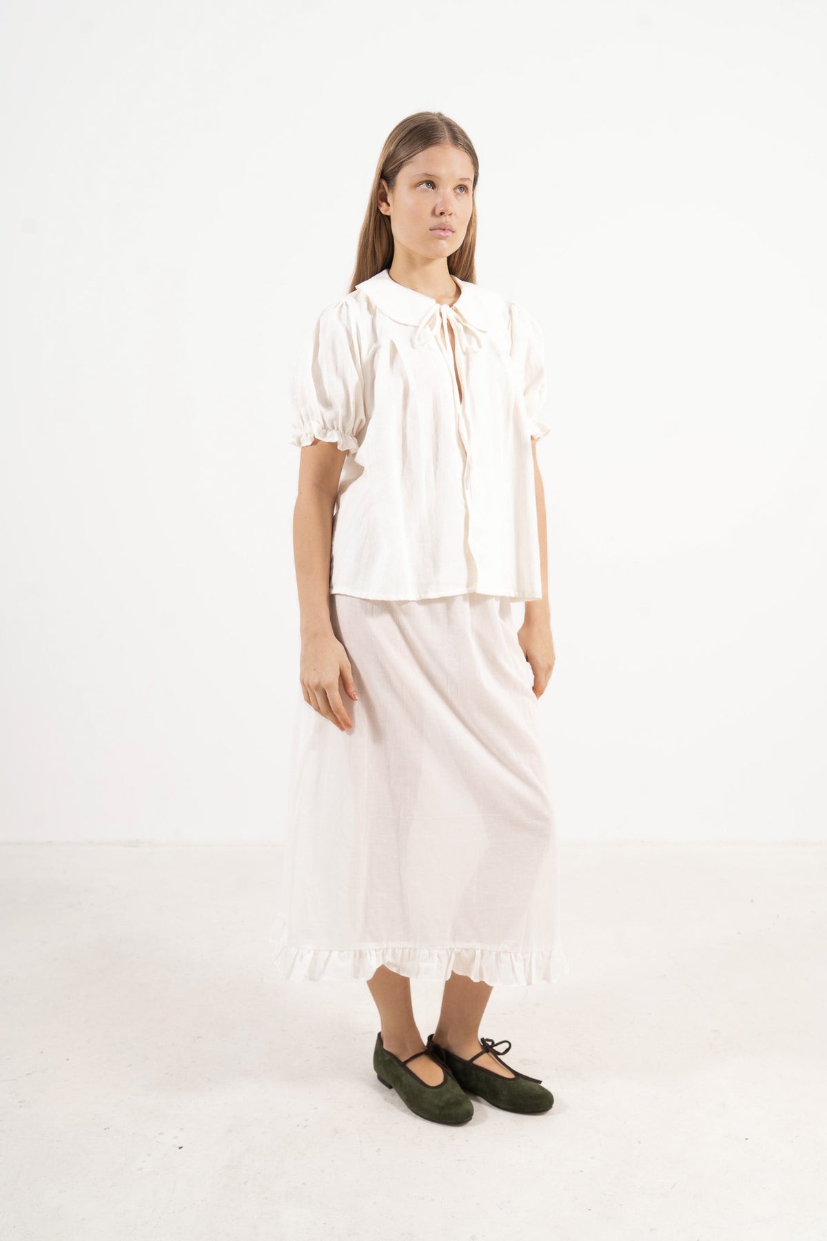 Profile studio portrait showcasing the versatile fit and pure, structural lines of the MOCHA Chérie blouse, perfect for warm summer days.