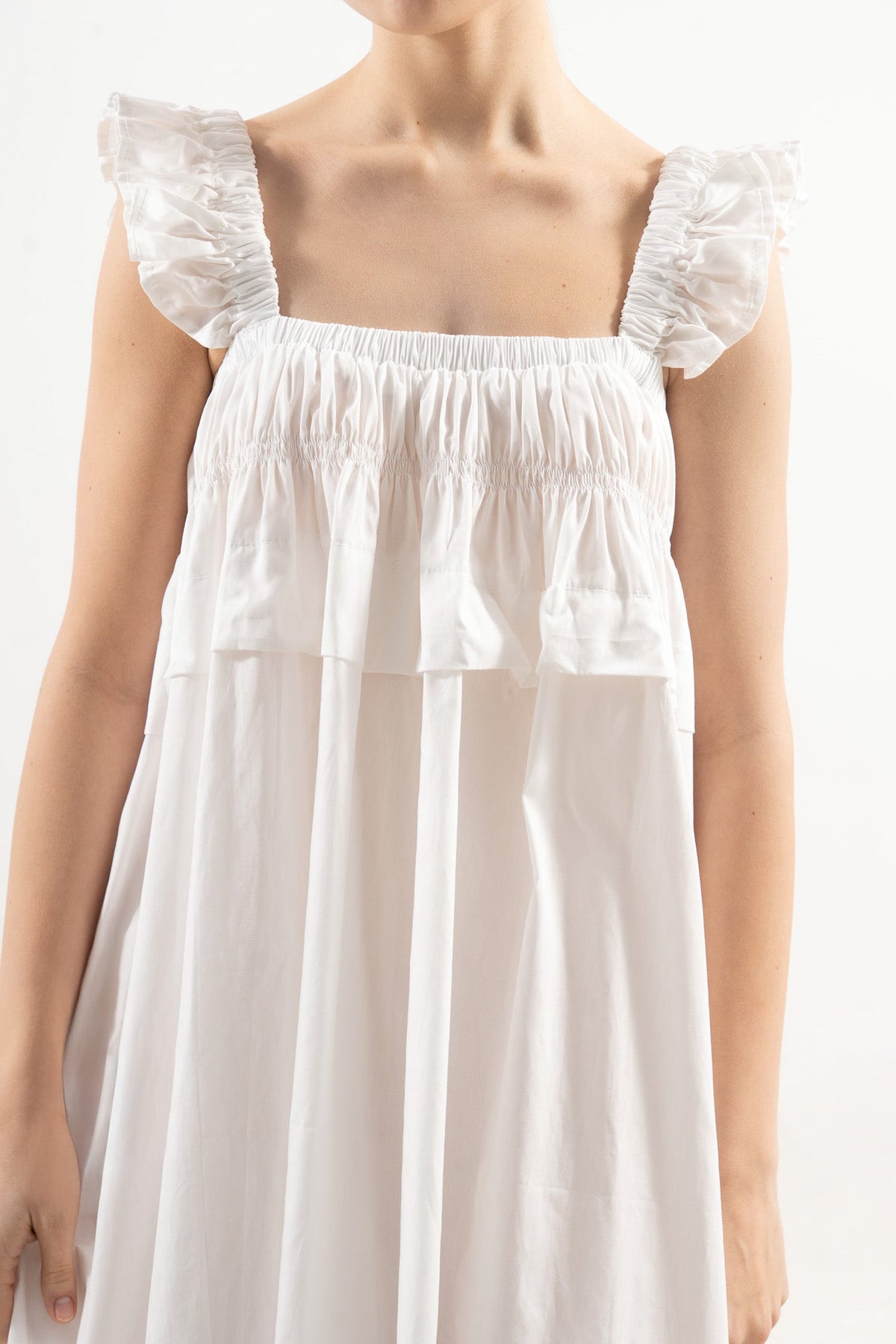 An exquisite close-up detail of the MOCHA Chloé dress, celebrating the fine organic cotton weave, beautiful delicate flower details, and superior fabric texture.