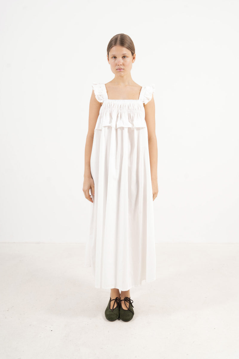 An elegant front view of the MOCHA Chloé long dress, meticulously crafted from the finest organic cotton and draped beautifully upon a pristine white floor.