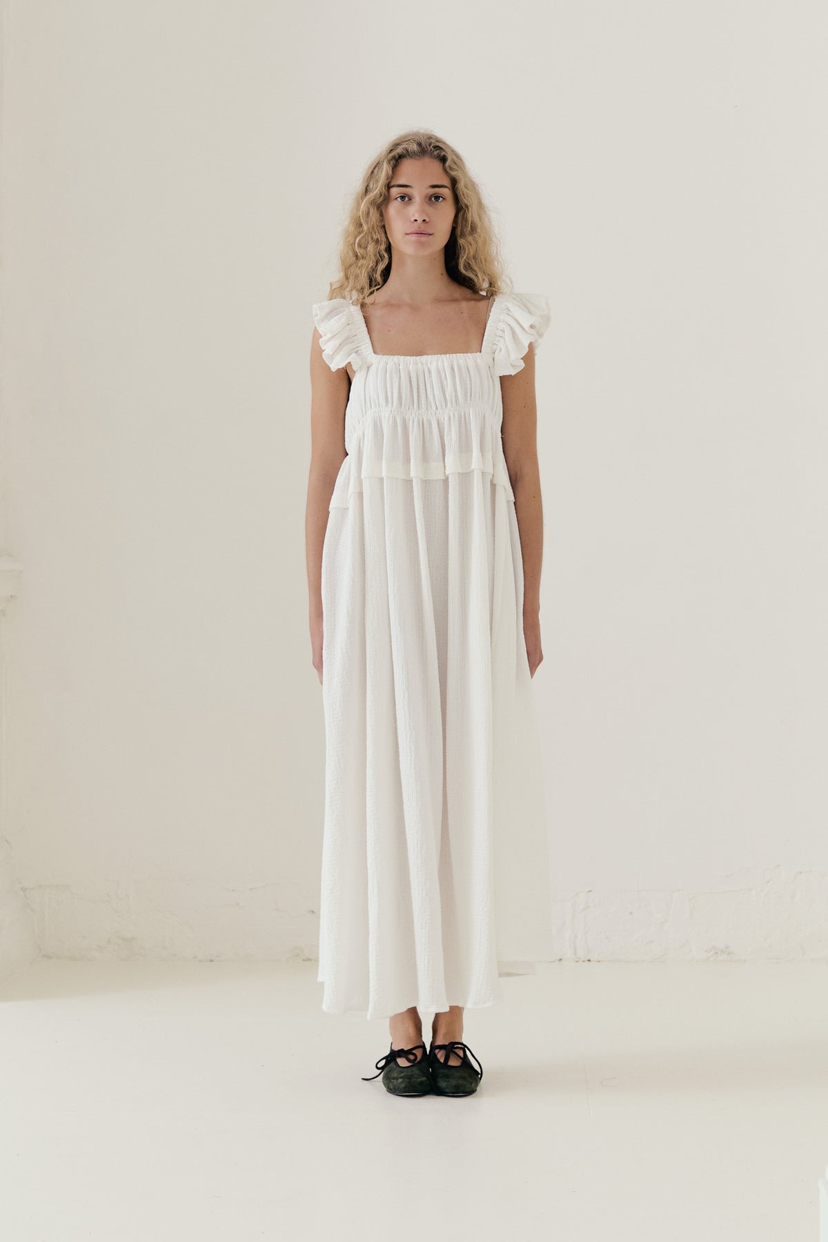 An elegant front view of the MOCHA Chloé long dress, meticulously crafted from the finest organic cotton and draped beautifully upon a pristine white floor.