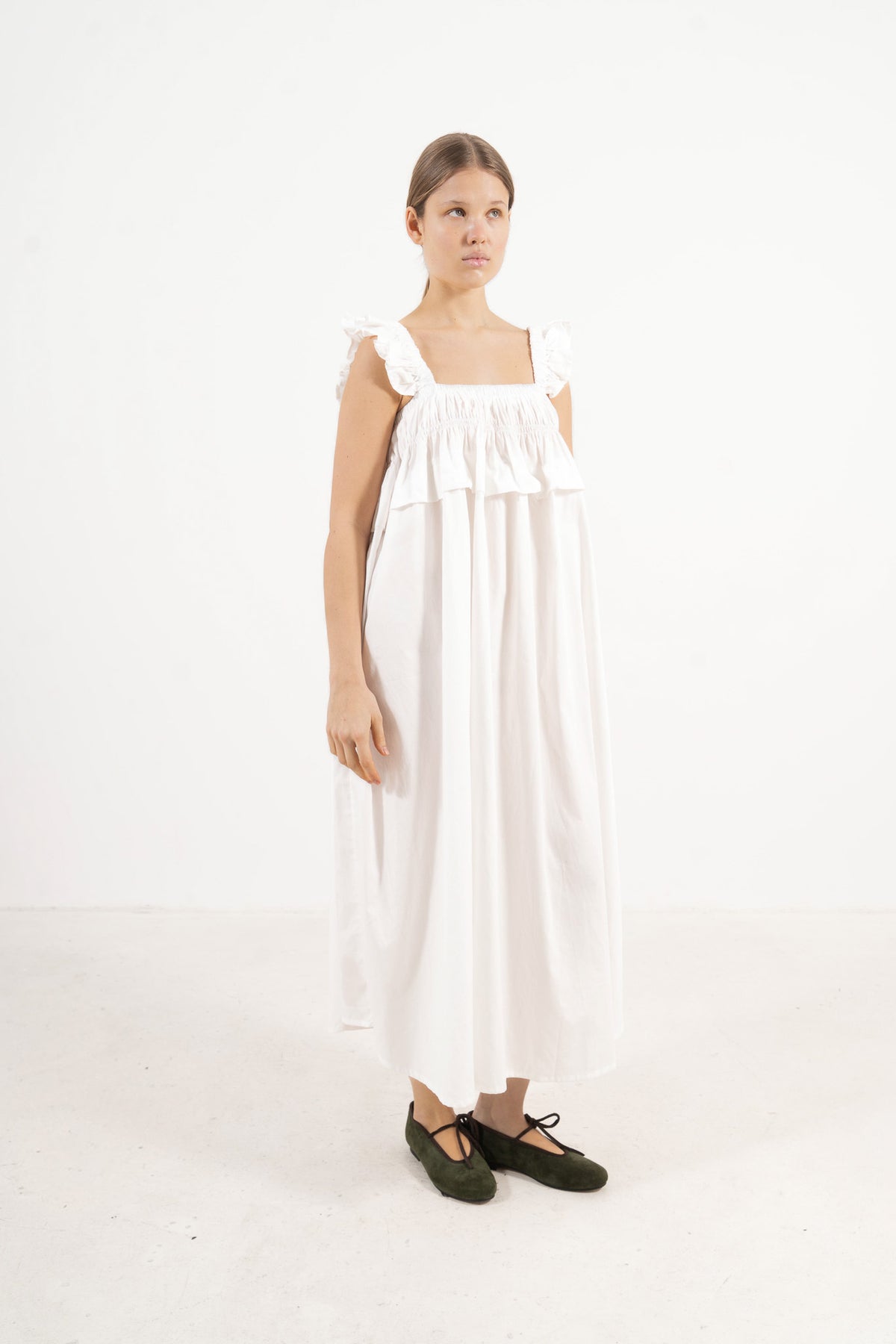 A poetic side angle view of the luxury organic cotton MOCHA Chloé garment, showcasing the charming, fluid silhouette cascading softly against a white backdrop.