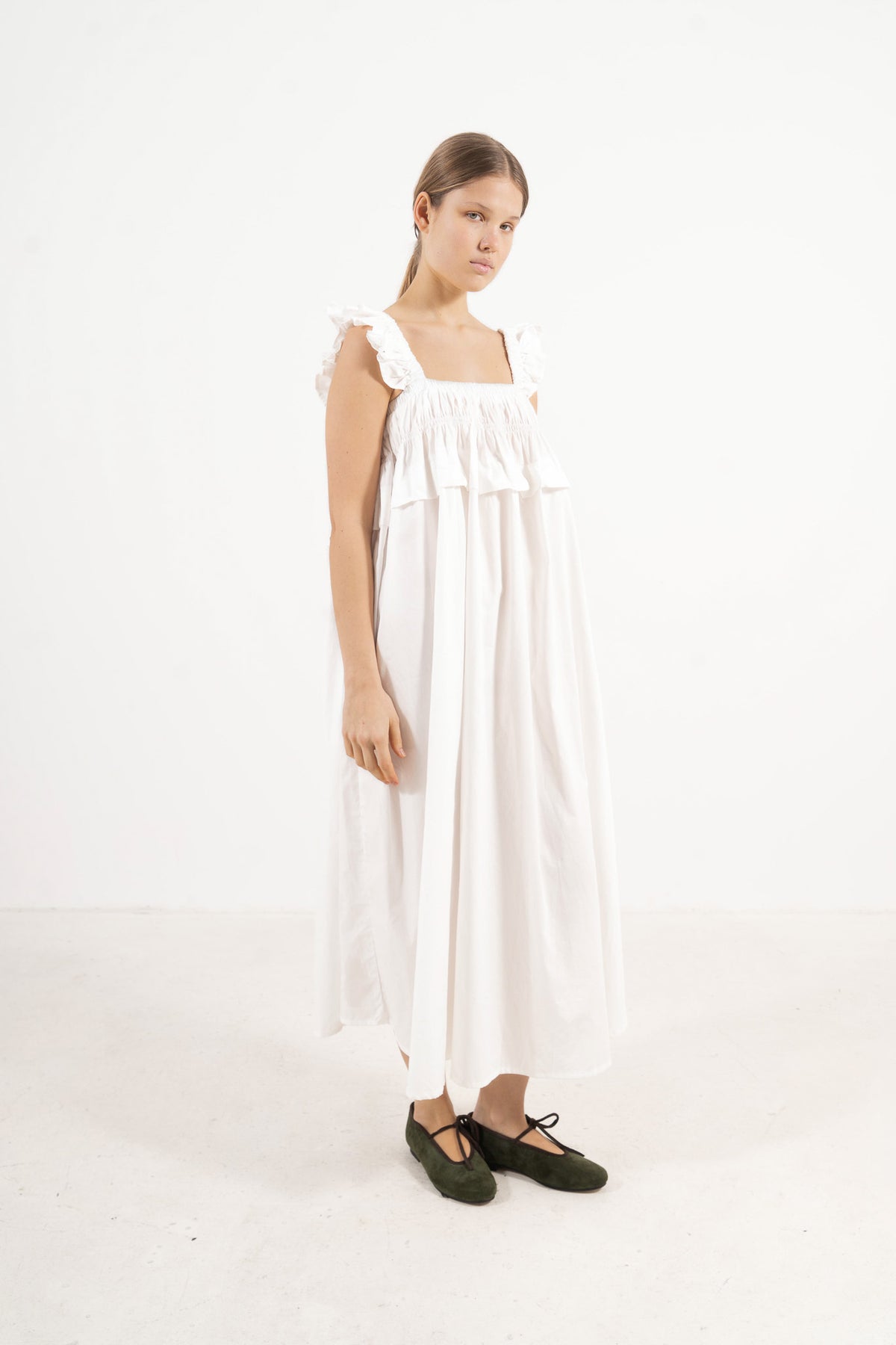 A poetic side angle view of the luxury organic cotton MOCHA Chloé garment, showcasing the charming, fluid silhouette cascading softly against a white backdrop.