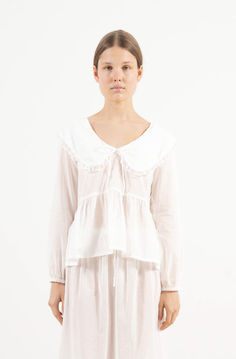 Front view studio portrait featuring a model in the white organic cotton Élodie blouse by MOCHA, capturing its quiet elegance and effortless lightness.