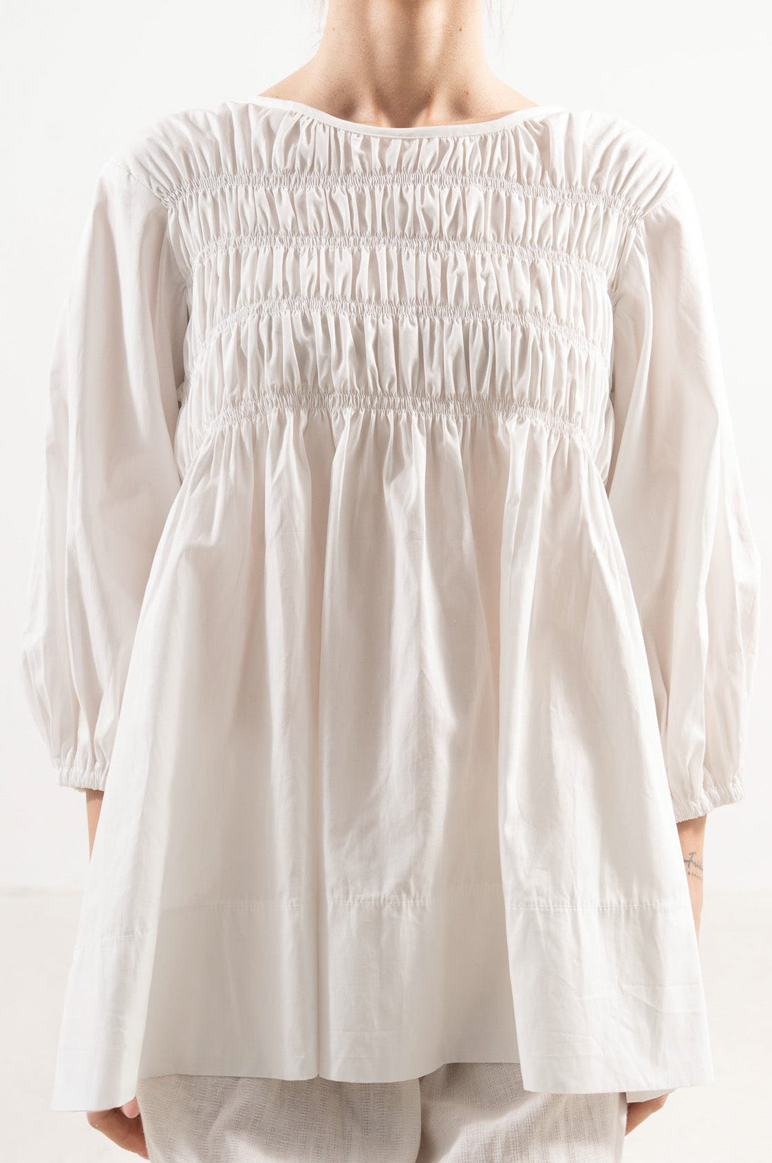 Close-up detail shot focusing on the intricate stitching, delicate collar features, and majestic texture of the pure MOCHA organic cotton weave