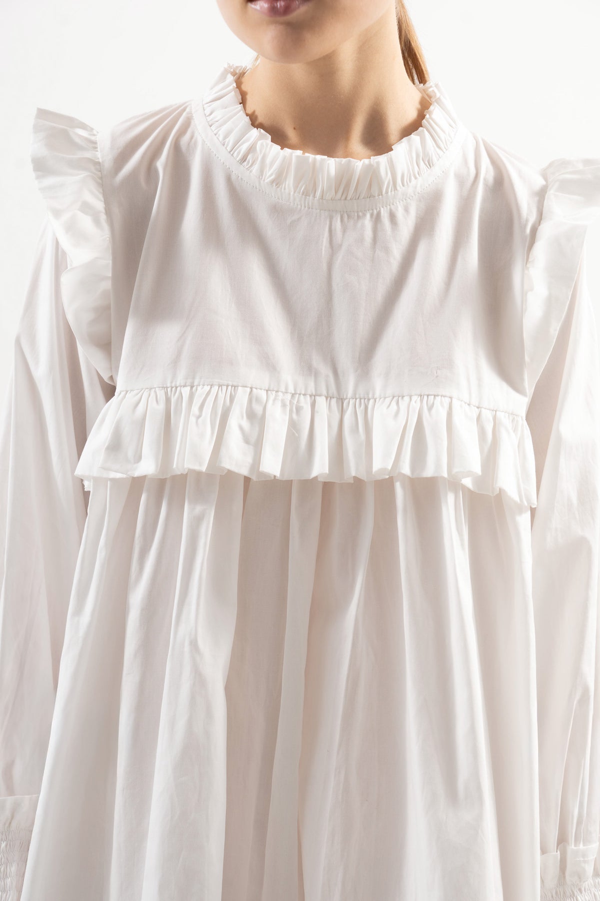 Close-up detail shot focusing on the intricate embellishments, premium organic cotton weave, and refined heritage details of the MOCHA dress.
