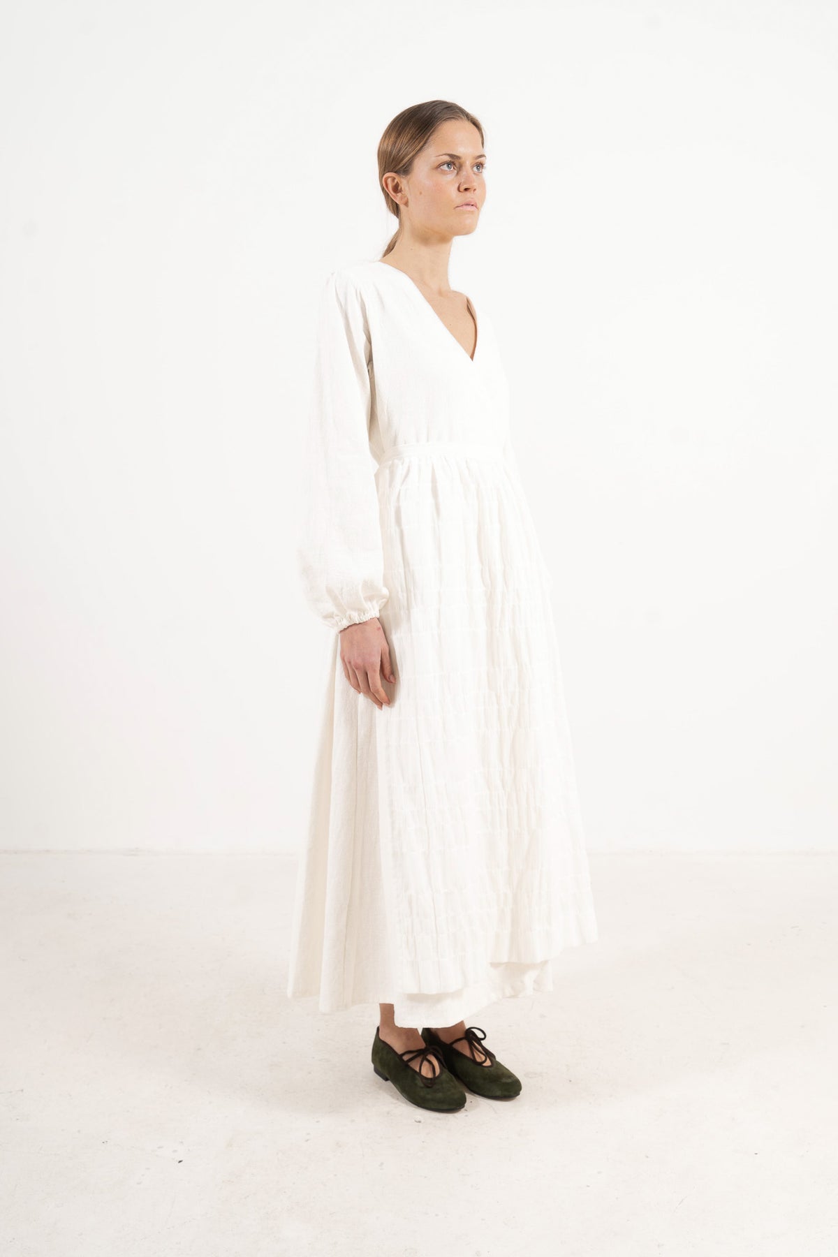 Studio lookbook portrait highlighting the relaxed fit, clean silhouette, and delicate volants of the MOCHA cotton apron.