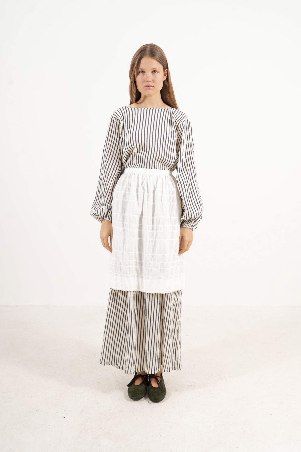 Front view lookbook image featuring a model wearing the ruffled Le Tablier mid apron by MOCHA, inspired by the quiet poetry of home.