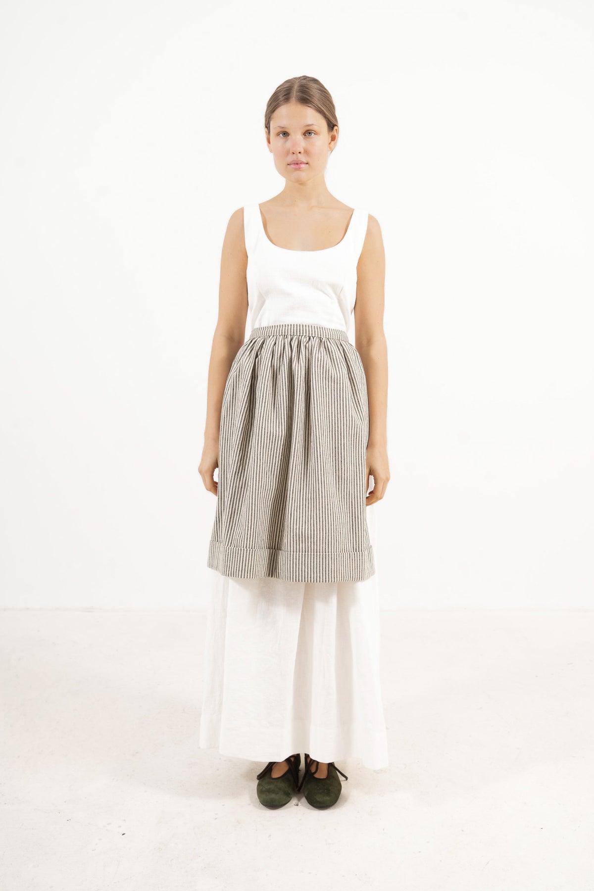 Front view lookbook image featuring a model wearing the ruffled Le Tablier mid apron in striped cotton by MOCHA, inspired by the quiet poetry of home.