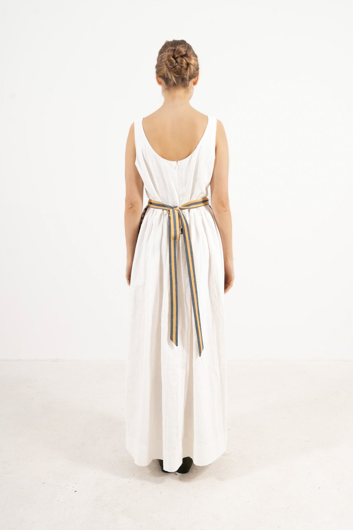 Back view of the striped mini apron on a model, showcasing the delicate tie straps and the fine craftsmanship of the piece.