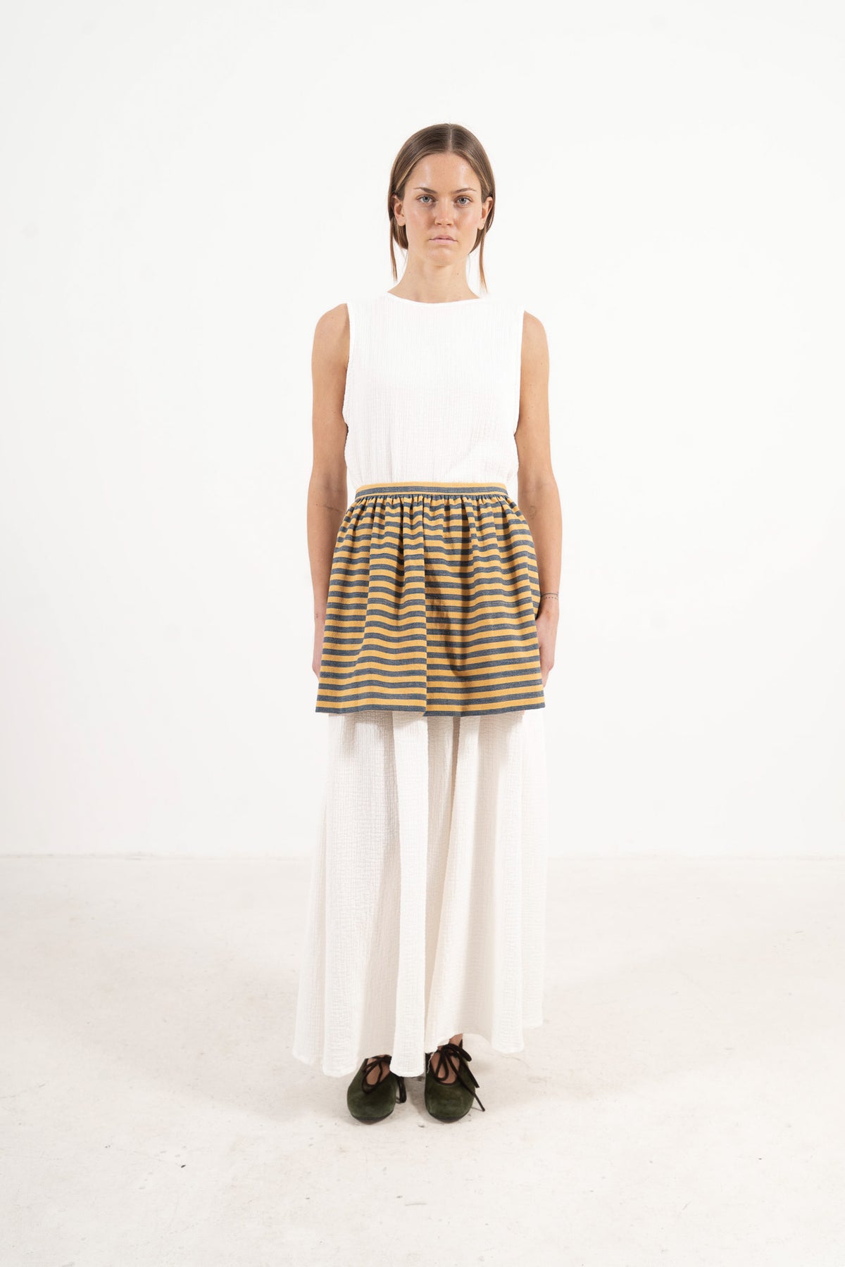 Front view lookbook image featuring a model wearing the ruffled Le Tablier mini apron in striped cotton by MOCHA, inspired by the quiet poetry of home.