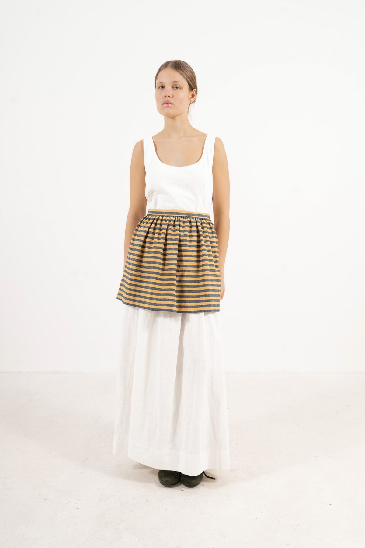 Front view lookbook image featuring a model wearing the ruffled Le Tablier mini apron in striped cotton by MOCHA, inspired by the quiet poetry of home.