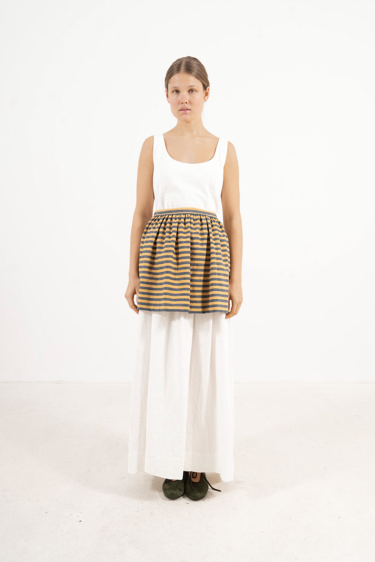  Front view lookbook image featuring a model wearing the ruffled Le Tablier mini apron in striped cotton by MOCHA, inspired by the quiet poetry of home.