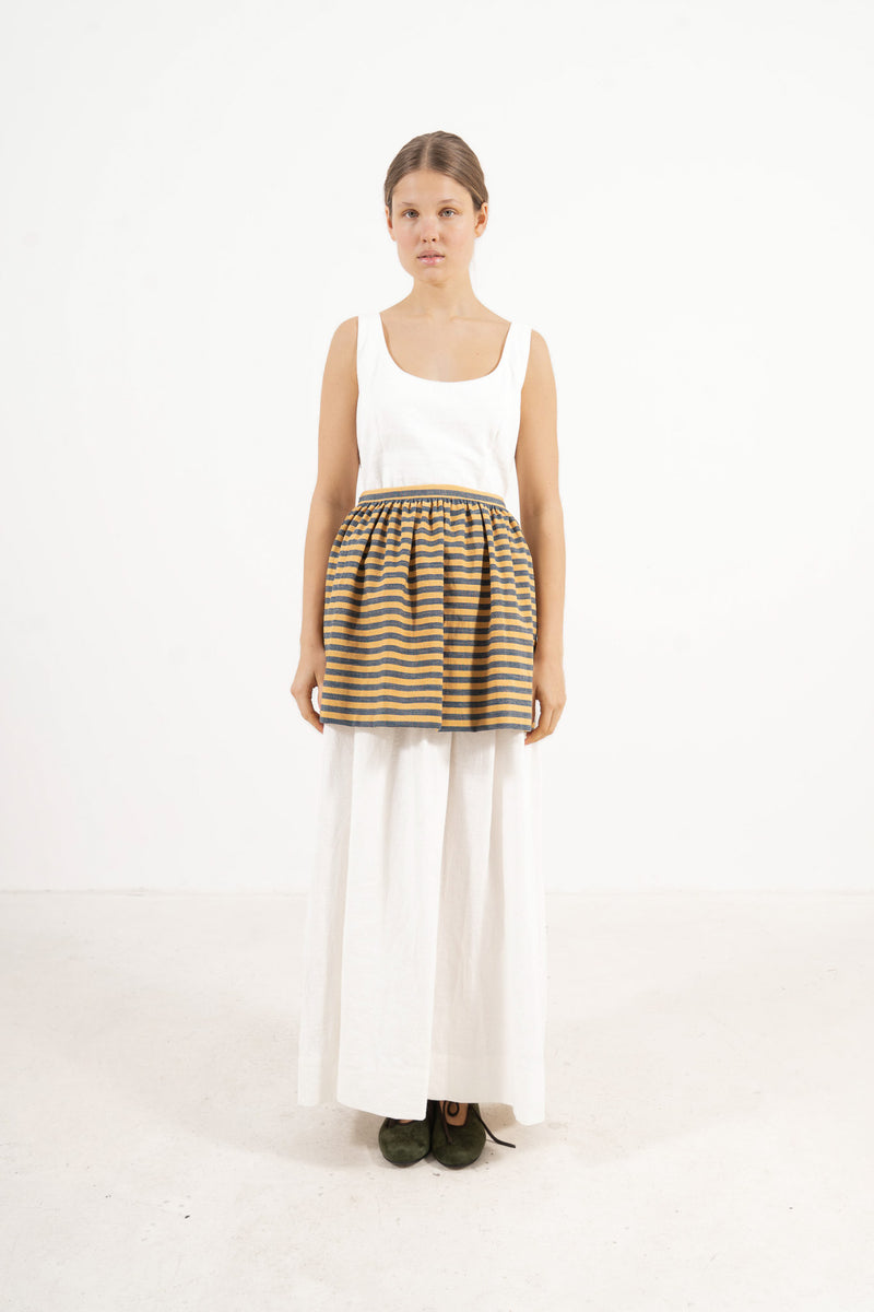 Front view lookbook image featuring a model wearing the ruffled Le Tablier mini apron in striped cotton by MOCHA, inspired by the quiet poetry of home.