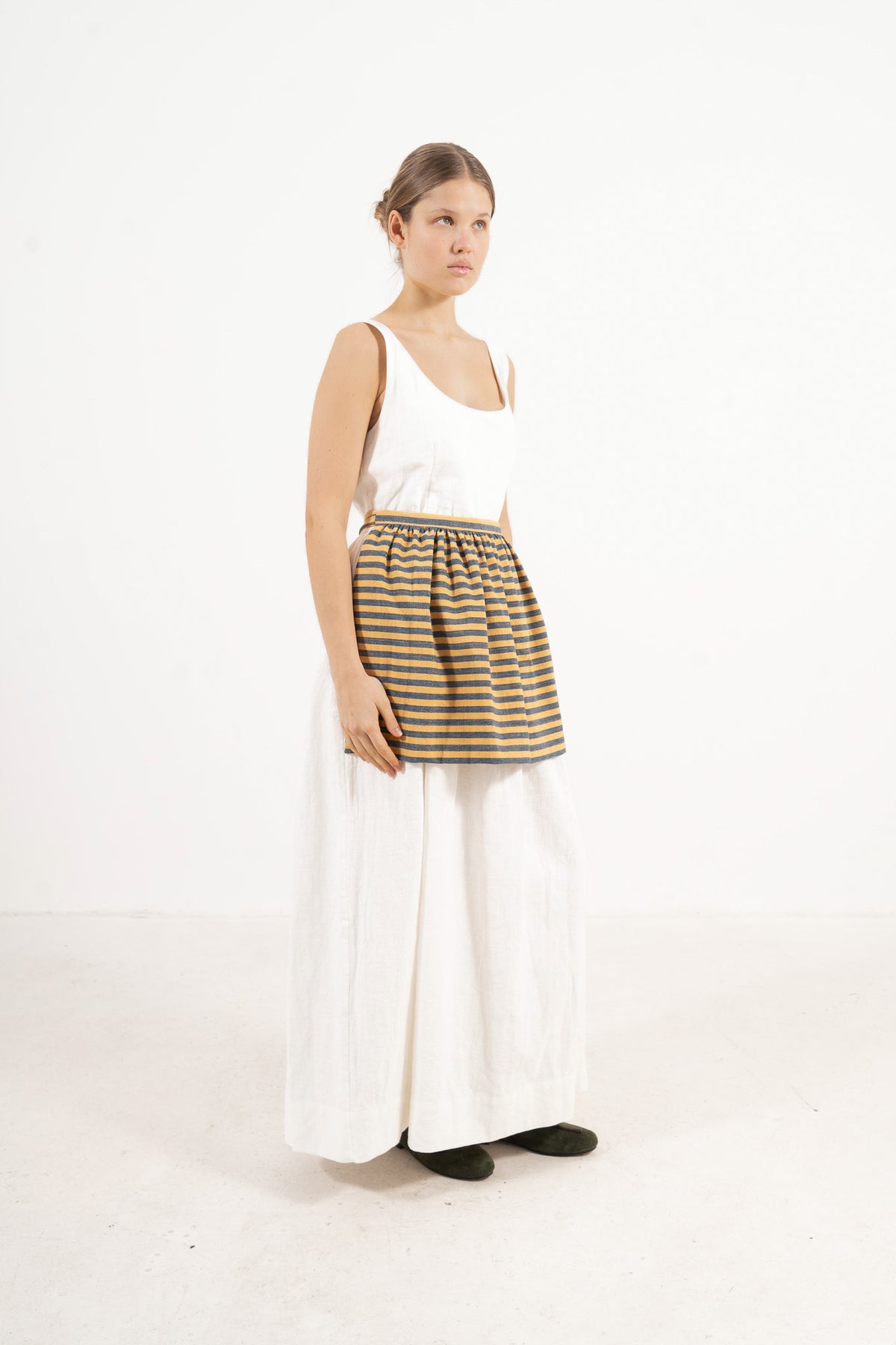 Studio lookbook portrait highlighting the relaxed fit, clean silhouette, and delicate volants of the MOCHA striped cotton mini apron.