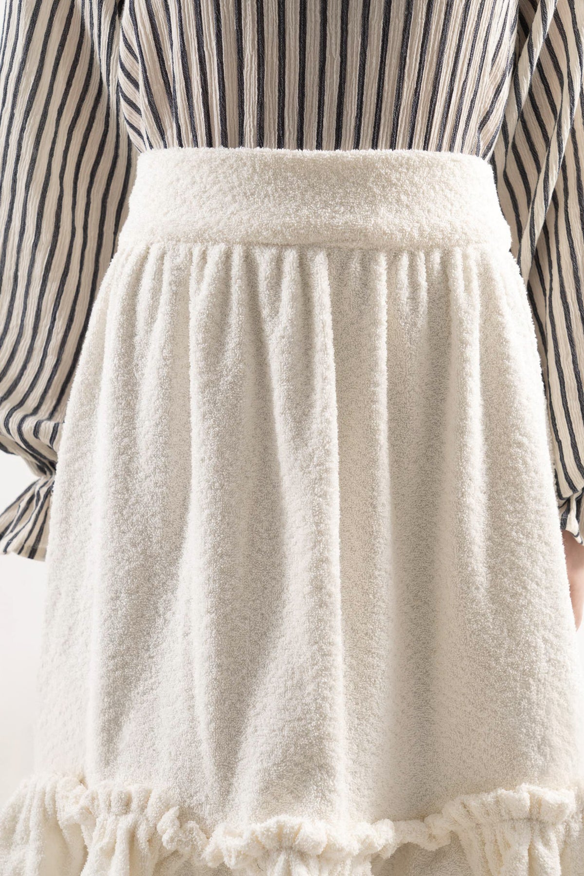 Close-up detail shot focusing on the delicate volants and premium cotton weave, celebrating the beauty of slow kitchen rituals.