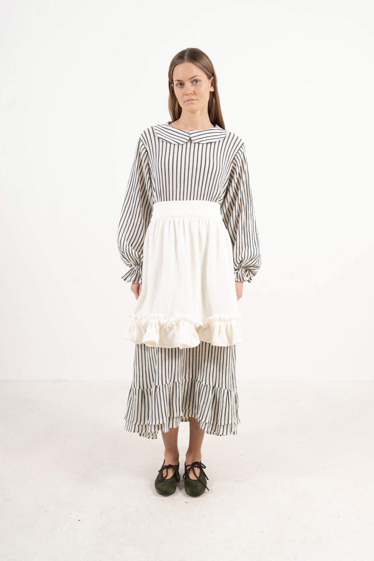 Front view lookbook image featuring a model wearing the ruffled Le Tablier Volanté mid apron by MOCHA, inspired by the calm poetry of home.