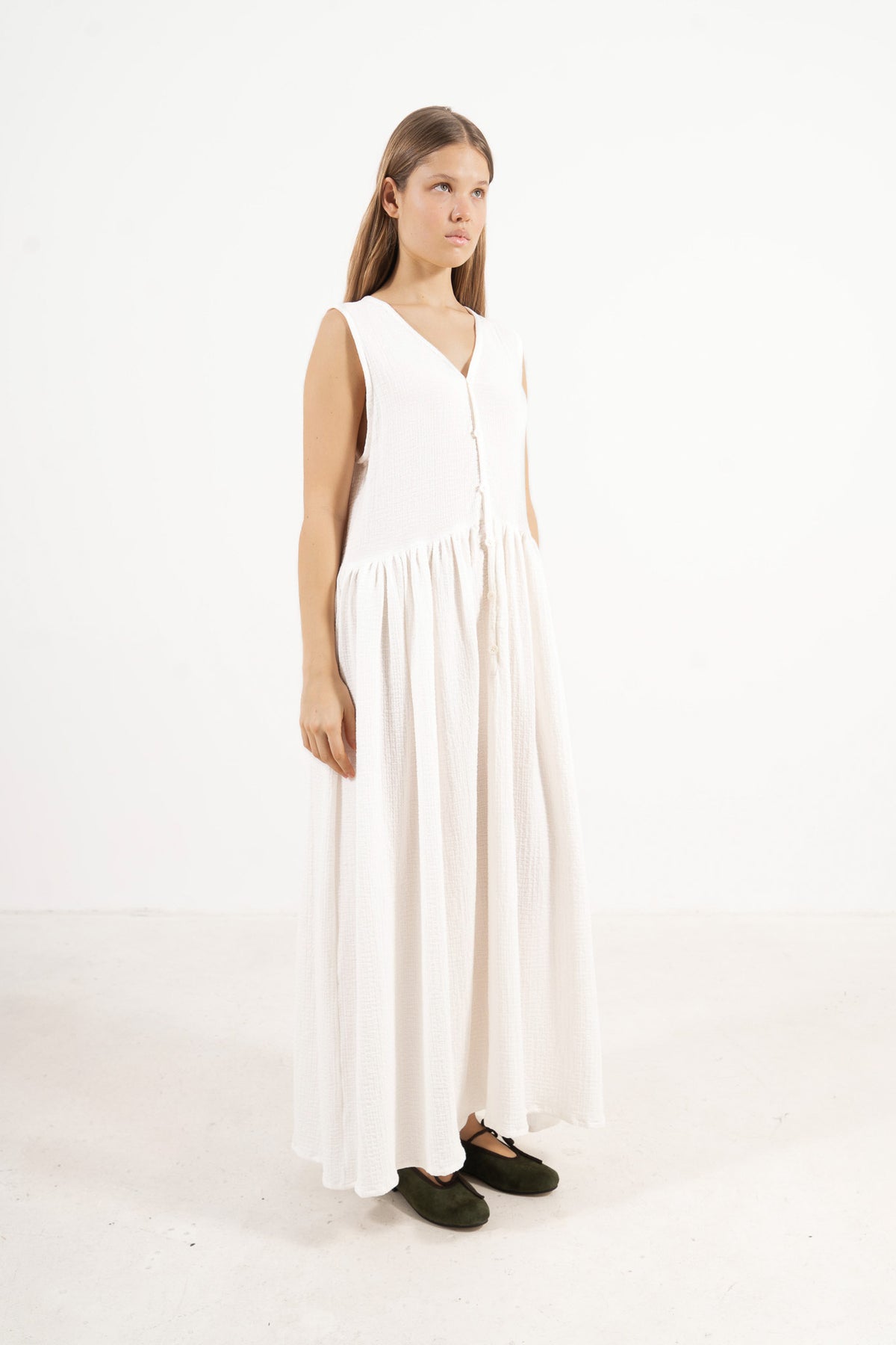 A sophisticated profile view of the standalone MOCHA Nuage dress in white soft cotton, revealing its graceful design lines resting on a clean white surface.