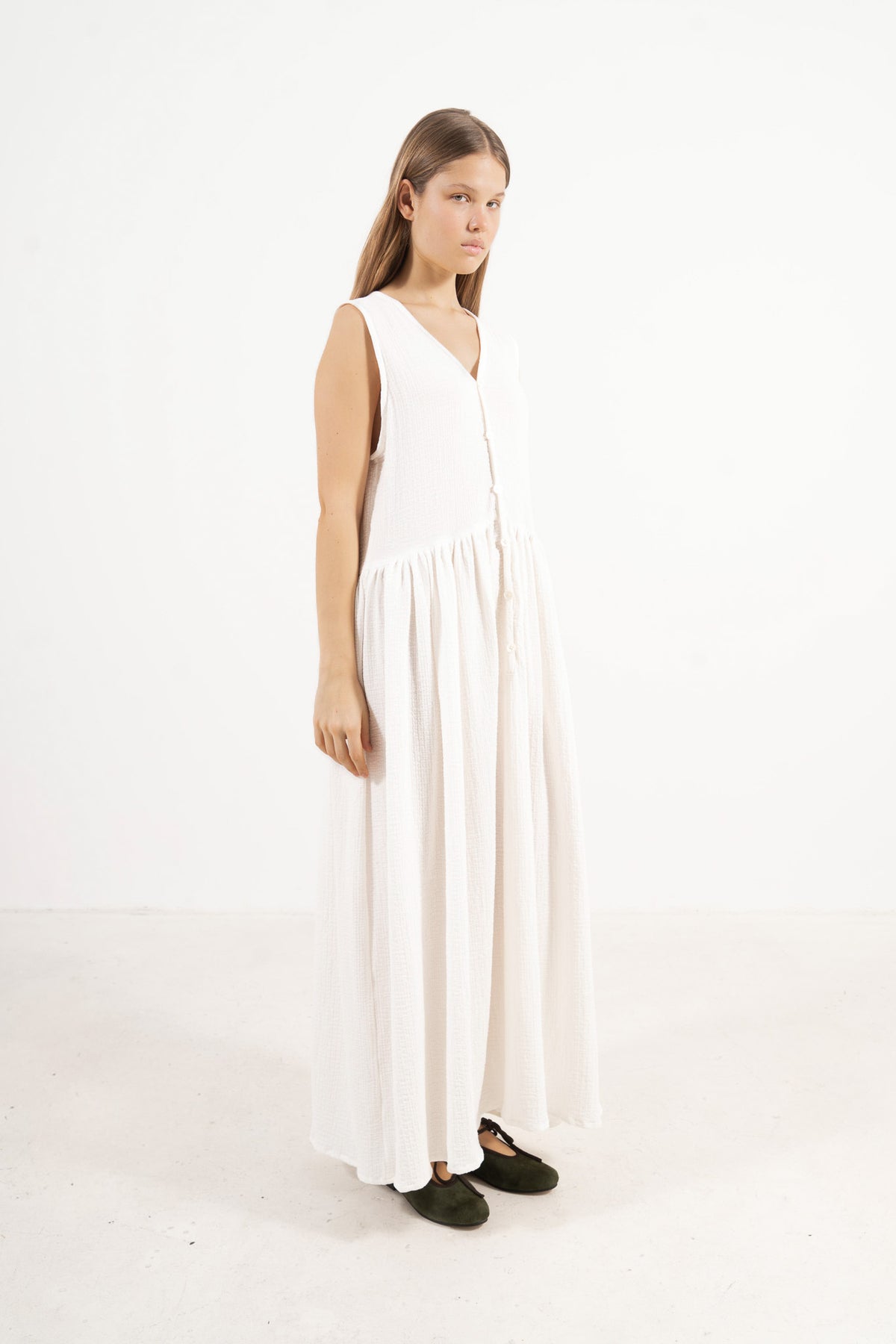 A poetic side angle view of the luxury soft cotton MOCHA Nuage garment, showcasing its light, timeless silhouette cascading softly against a white backdrop.