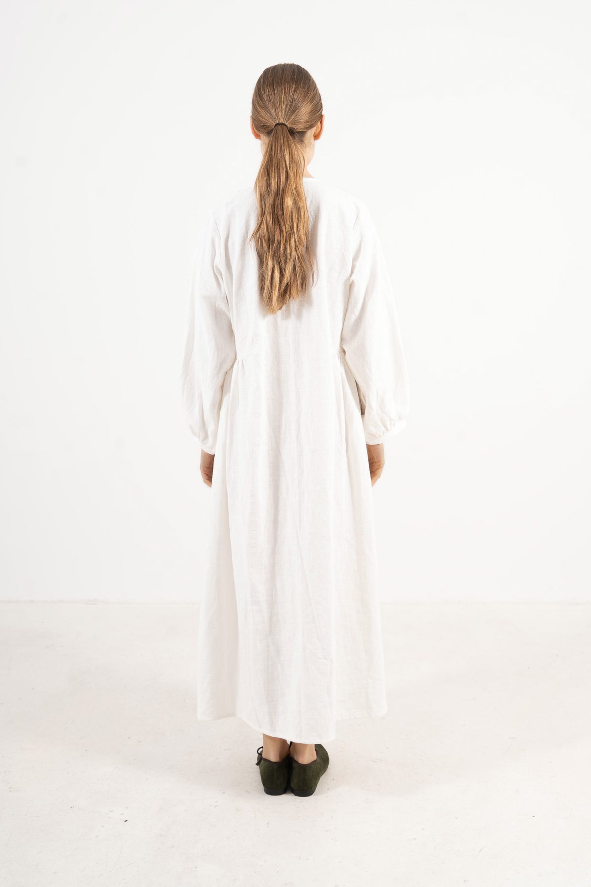 Back silhouette of the timeless Madeleine Dress, illustrating the composed drape and refined tailoring signature to MOCHA.