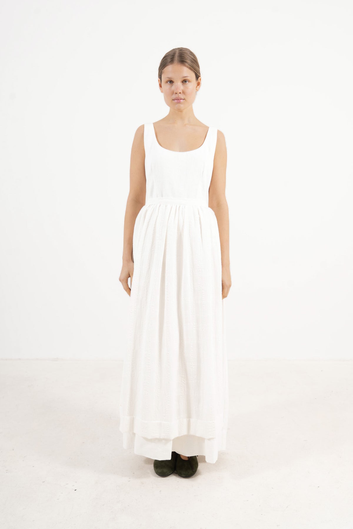 Le Tablier Long Apron from the POÈME La Cuisine line by MOCHA, highlighting the clean silhouette and delicate volants in a front lookbook shot.