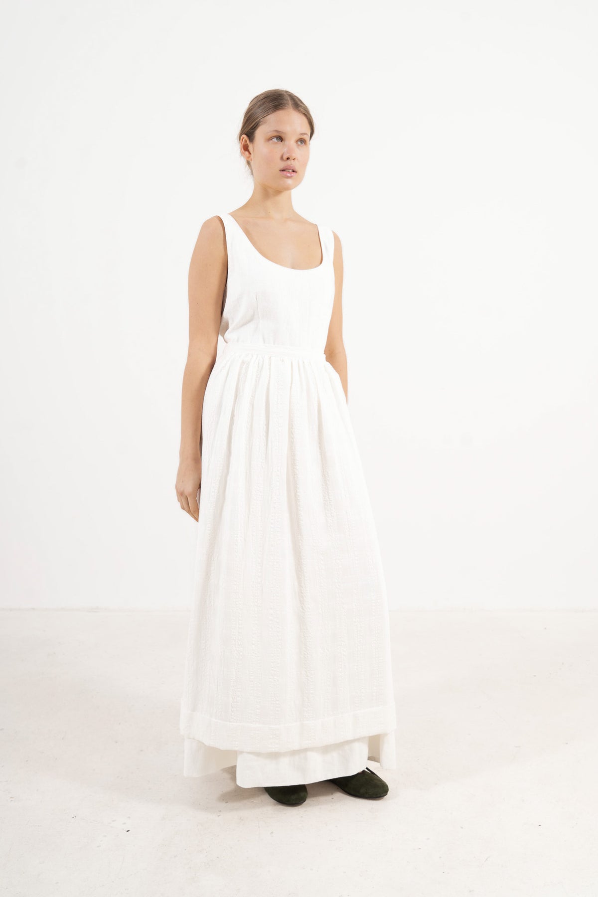 Le Tablier Long Apron from the POÈME La Cuisine line by MOCHA, highlighting the clean silhouette and delicate volants in a front lookbook shot.