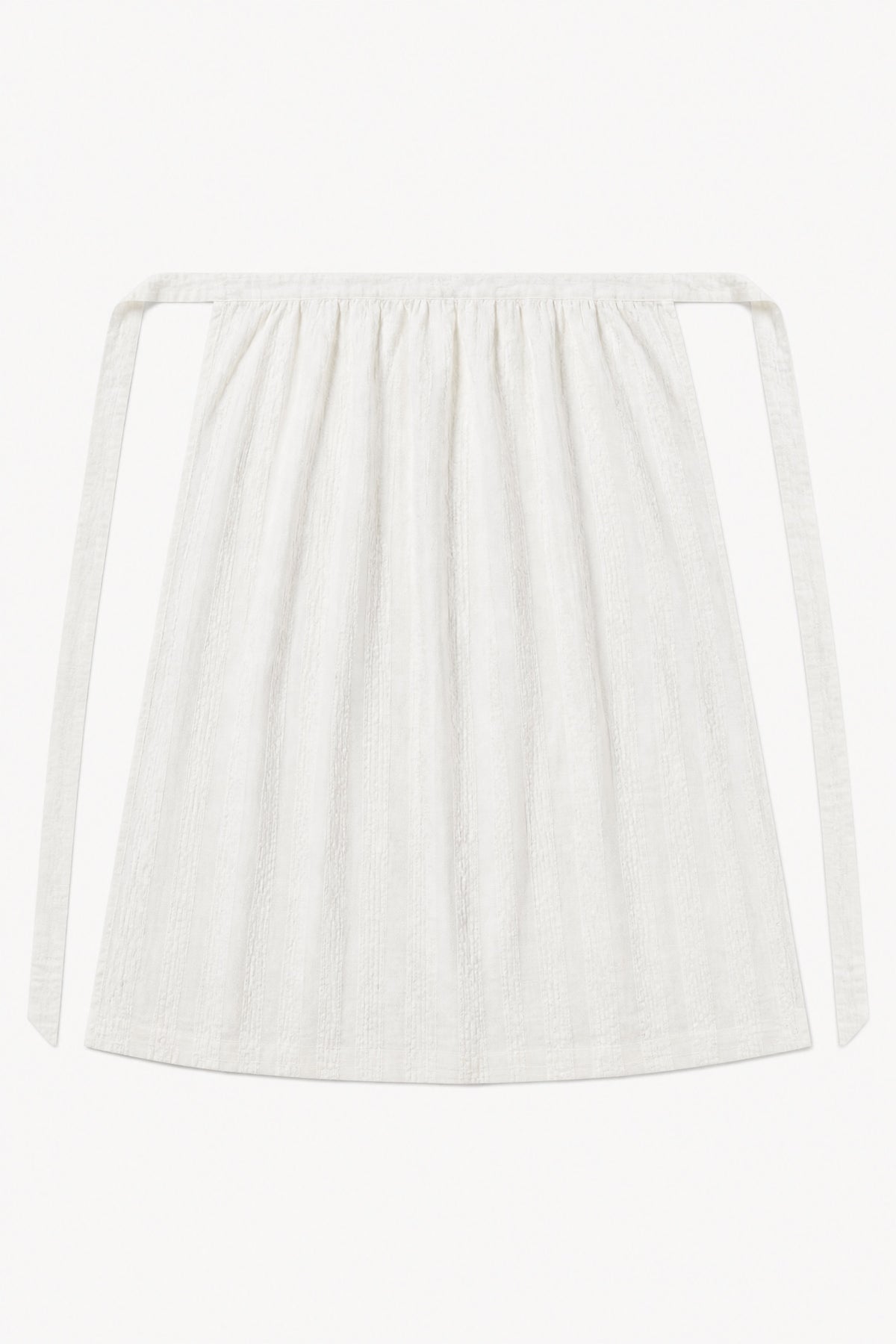Le Tablier Long Apron from the POÈME La Cuisine line by MOCHA, highlighting the clean silhouette and delicate volants in a front lookbook shot.
