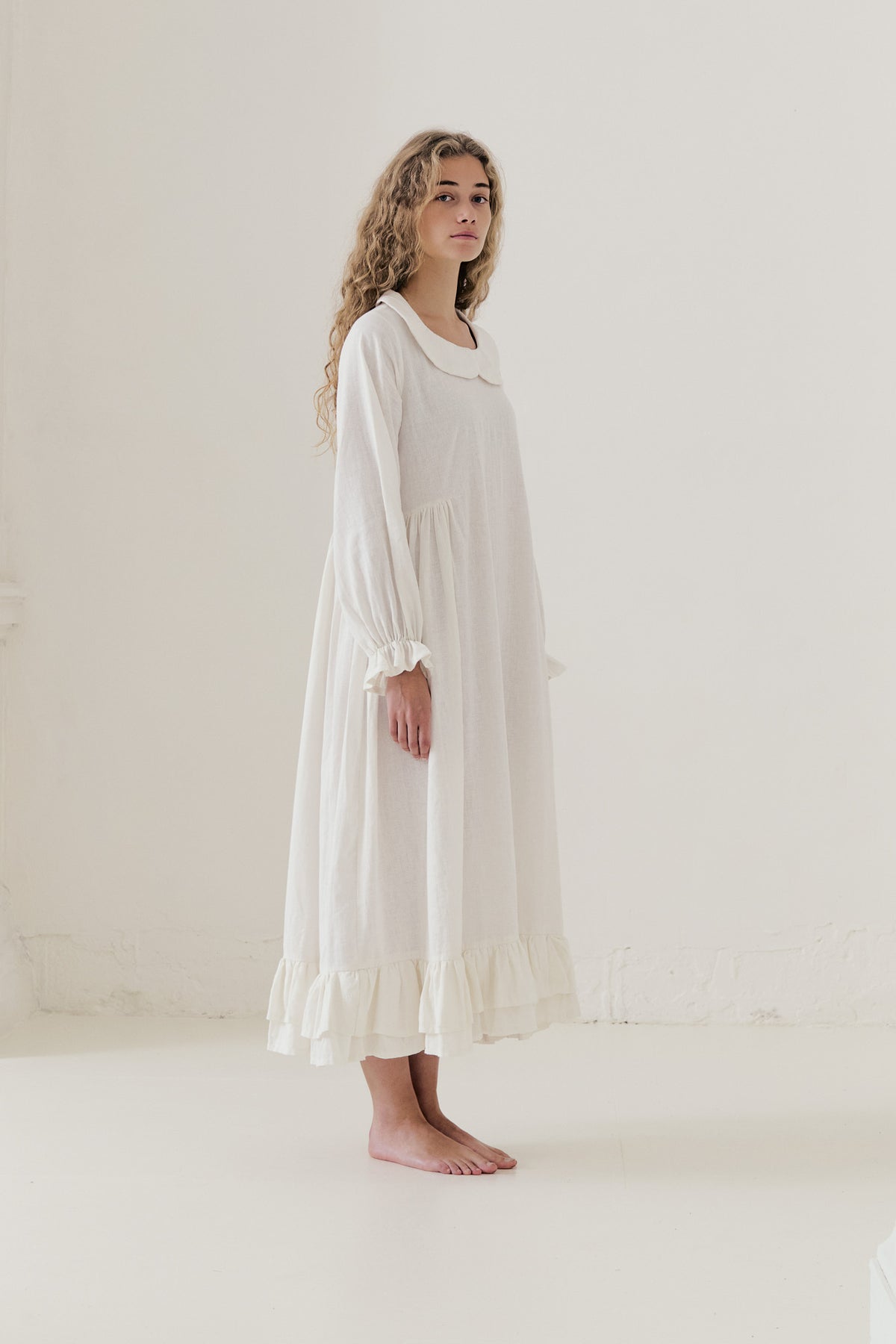 Side lookbook capture of the white cotton dress, emphasizing how the flowing fabric moves easily with every step.