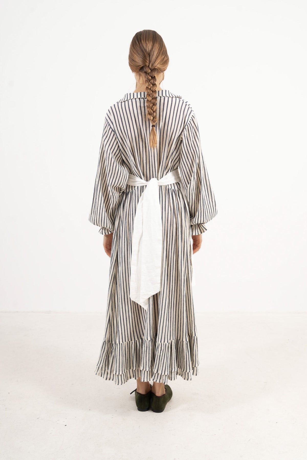 Back view of the timeless striped cotton dress on a model, capturing a gentle aesthetic inspired by air, movement, and calm days.