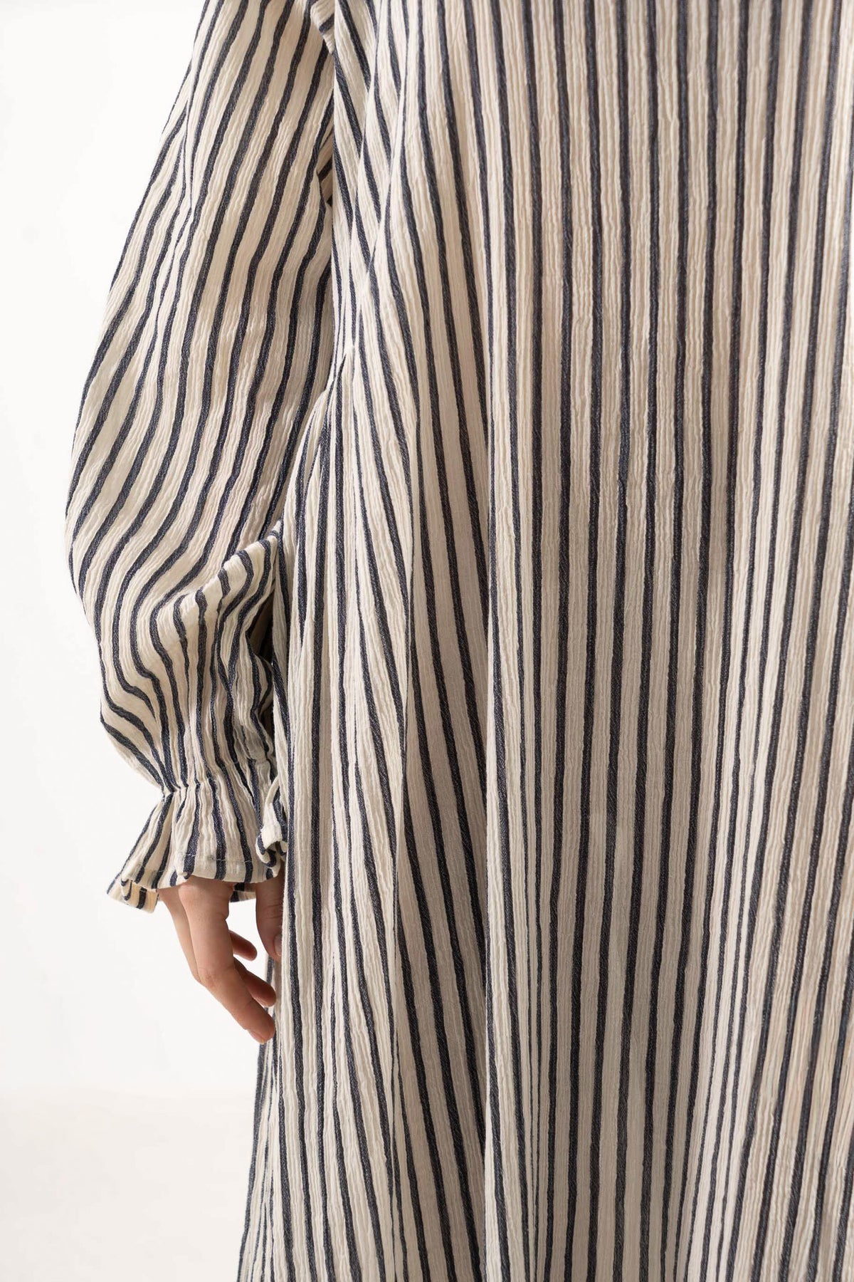 Close-up detail shot focusing on the delicate collar, fine ruffled details, and premium texture of the MOCHA striped cotton weave.