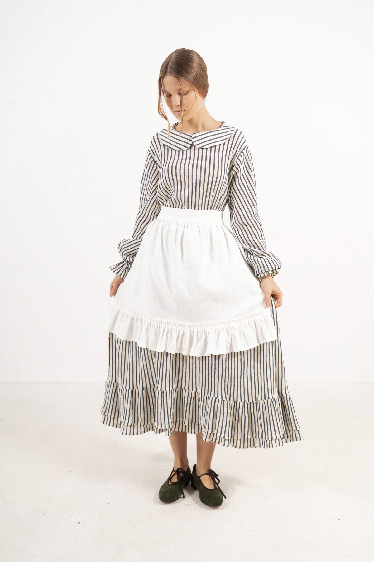 Woman wearing a striped dress with a white apron on a white background