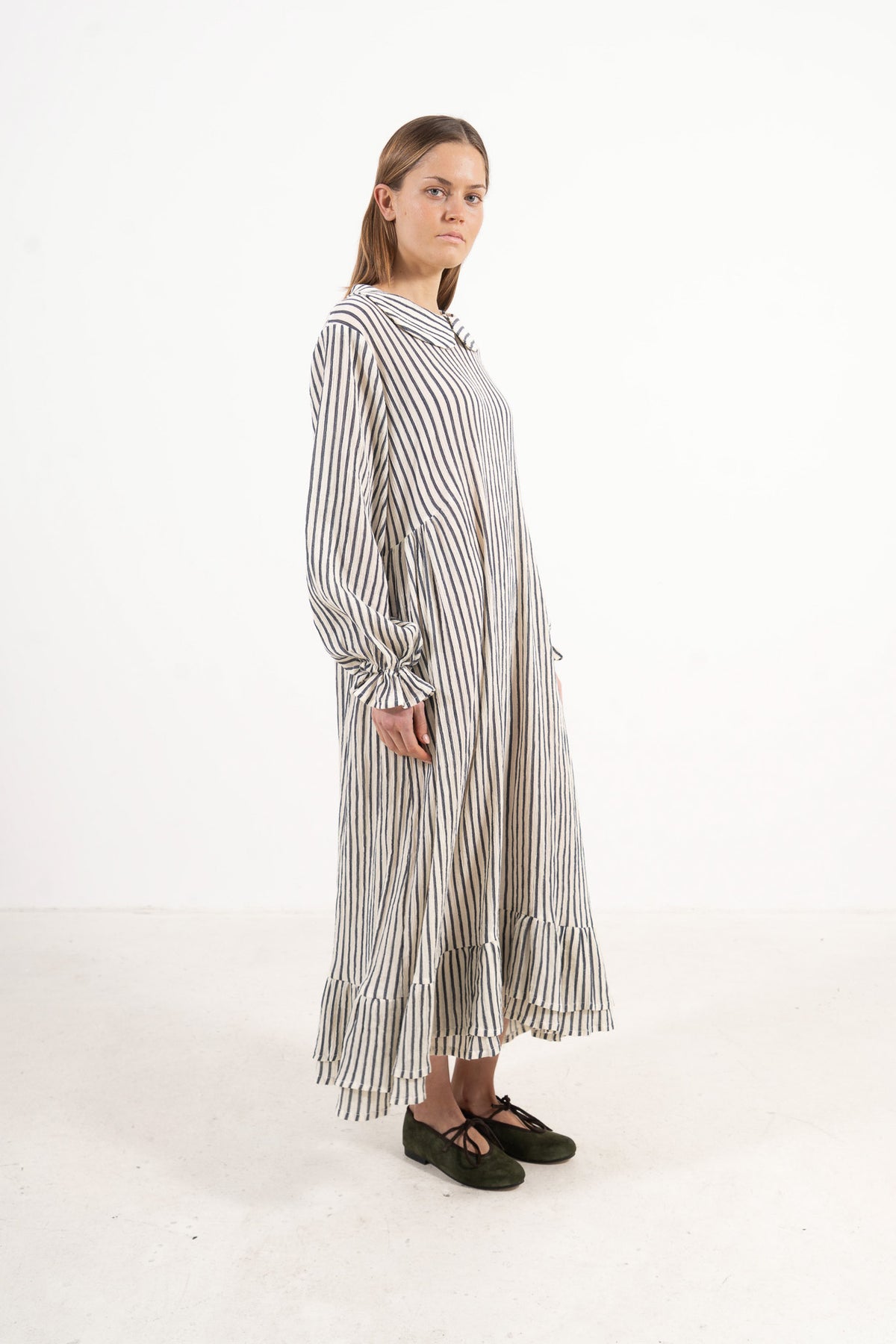 Profile studio portrait showcasing the refined long silhouette and graceful design of the MOCHA Sillage dress.